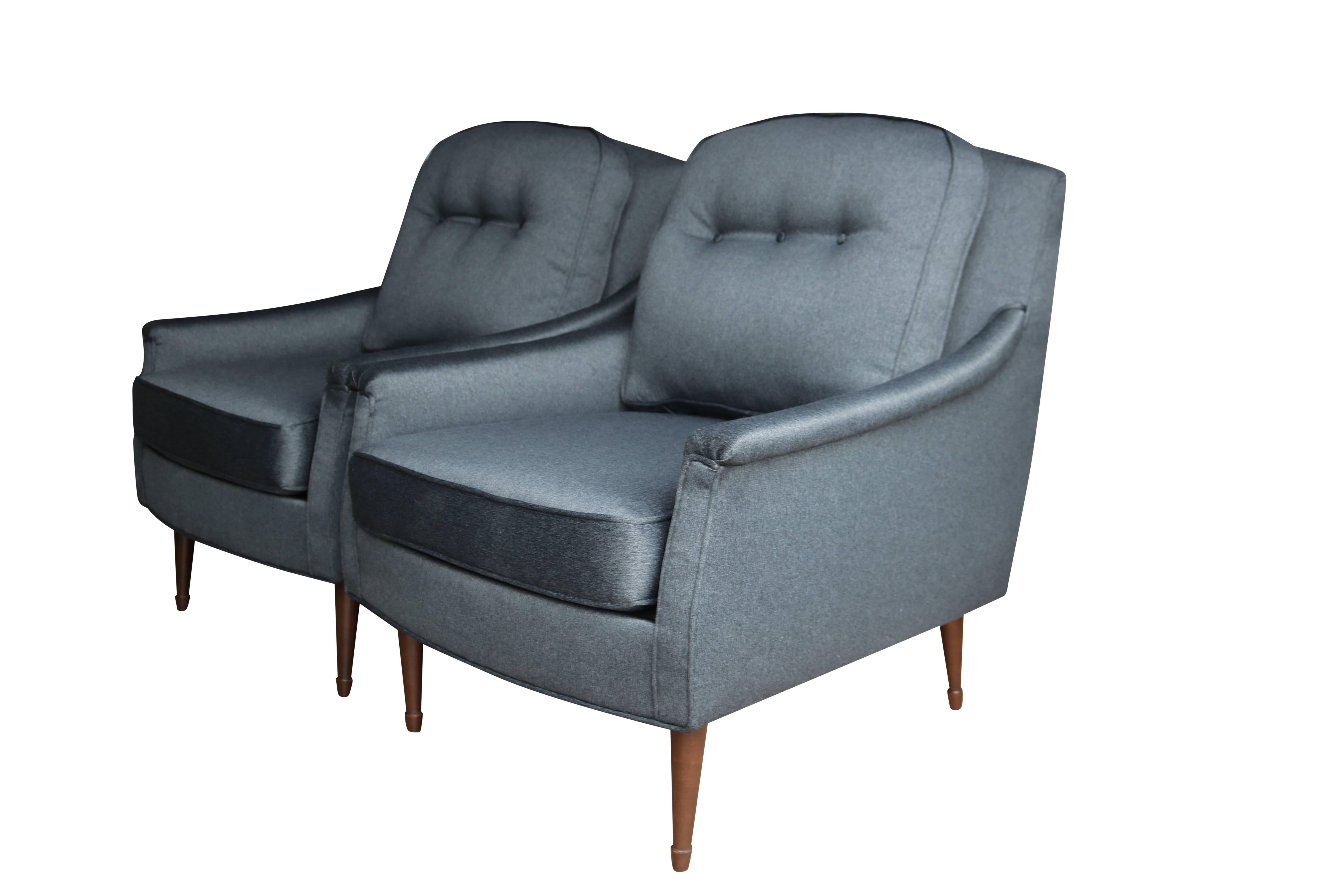 Newly upholstered in a lovely gun metal grey fabric with the slightest hint of sheen, these vintage armchairs will bring masculine sophistication to any room. Walnut legs compliment the look.