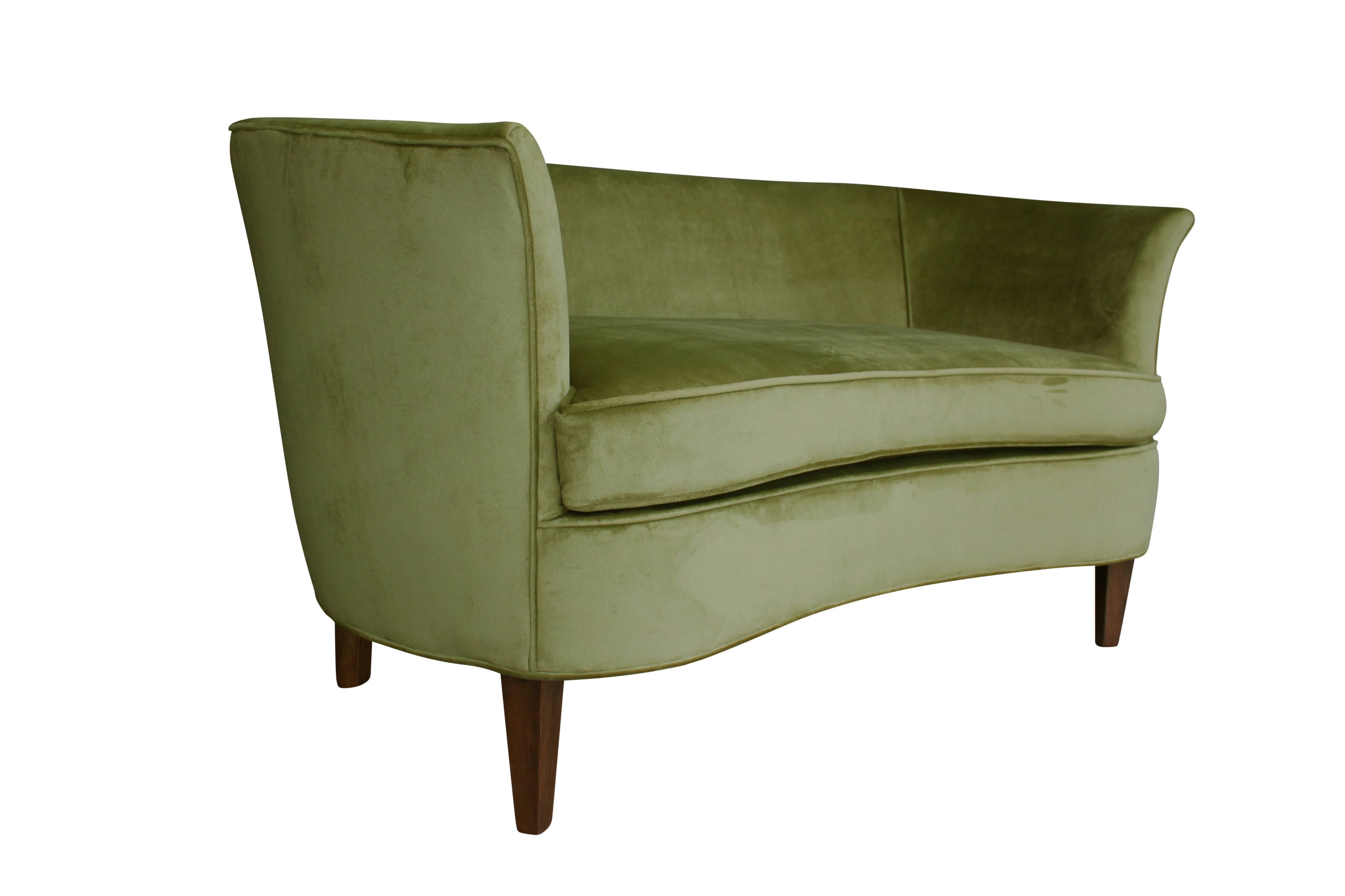 This lovely sculptural settee or loveseat has walnut legs an undulating from cushion and slightly flared arms. It has been completely restored and covered in a lush parrot green mystere velvet. Perfect for small spaces or wherever a pop of color is