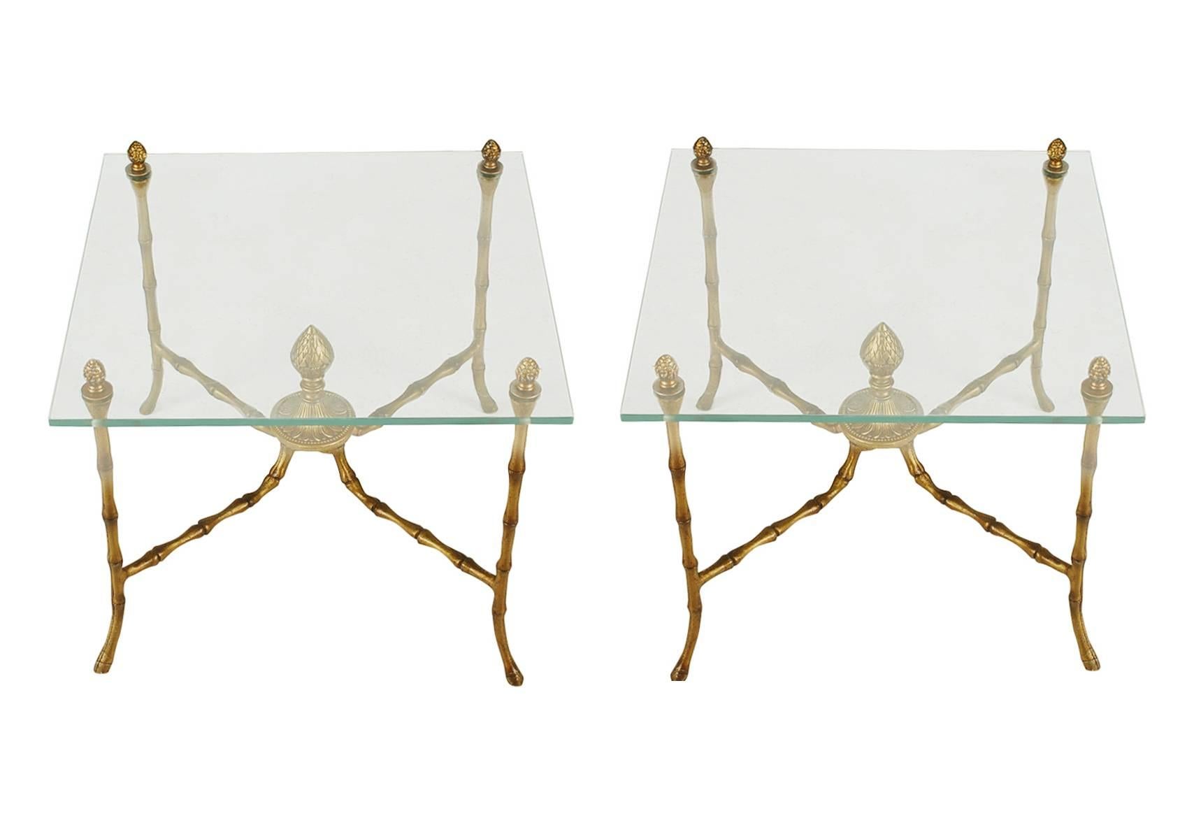 A sophisticated pair of end tables with a brass or gold gilded type finish. They feature heavy Minimalist metal frames with floating glass tops. Probably Italian or French. 

In the style of: Maison Jansen, Maison Bagues.