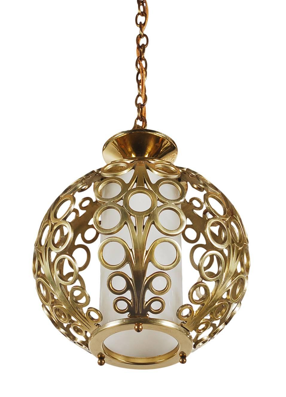 A beautifully designed brass pendant lamp circa 1960's. It features solid brass construction with a glossy milk glass center diffuser. Tested, working, and ready for immediate use. 

In the style of: Tommi Parzinger, James Mont, Dorothy Draper