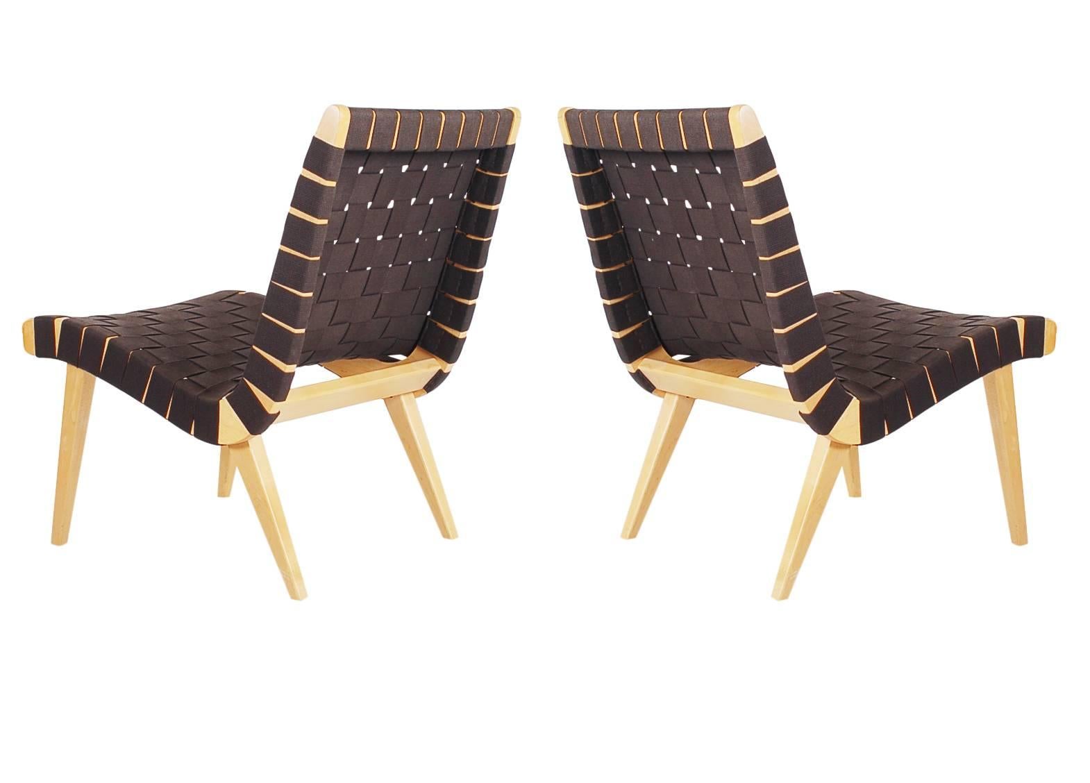 An iconic set of matching lounge chairs designed by Jens Risom and produced by Knoll. They feature solid maple frames with black cotton strapping. Manufacturers labels on both.
