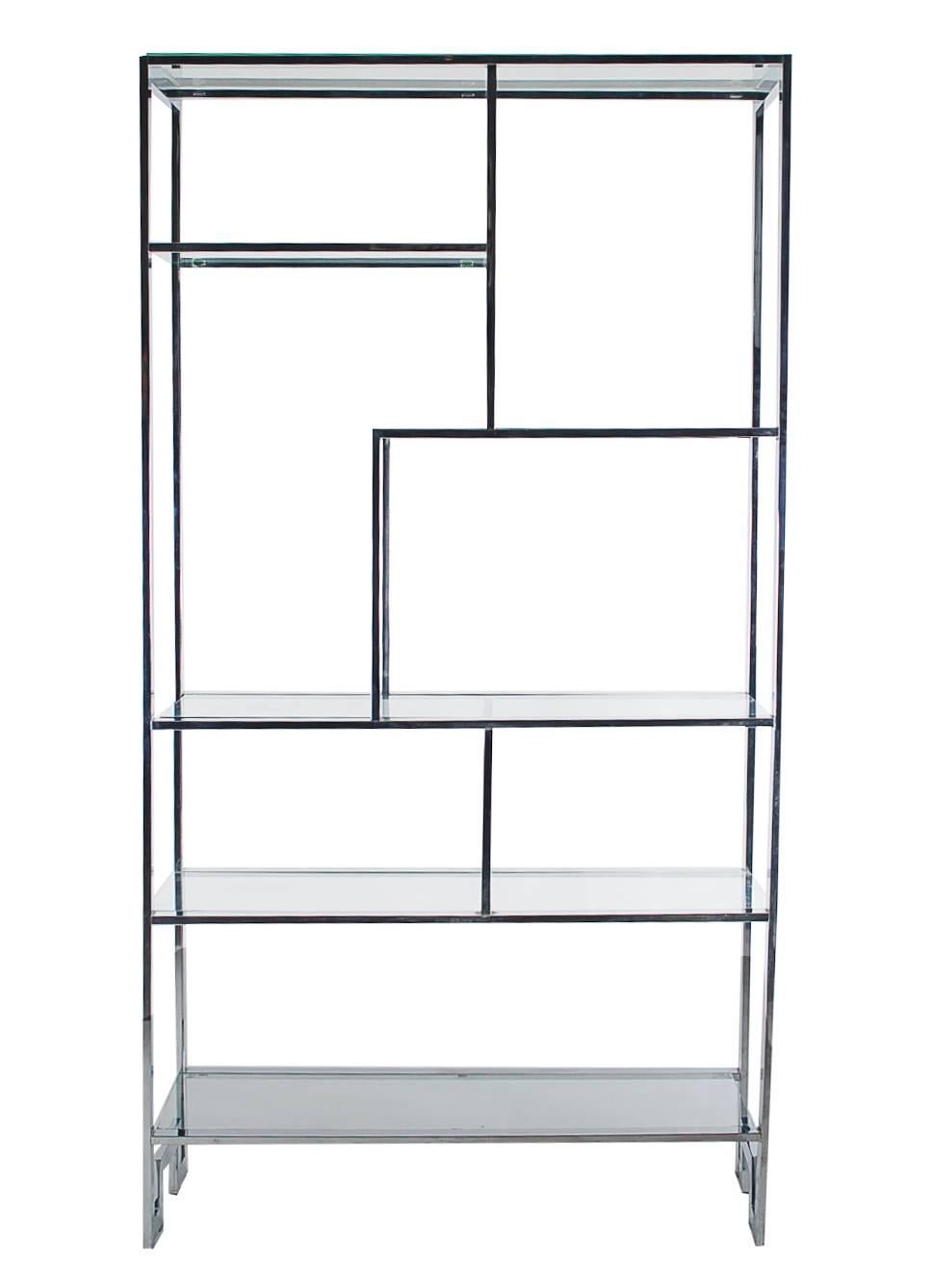 A large asymmetrical chrome and glass etagere in the style of Milo Baughman. It features a heavy chrome flat bar frame with various sized glass shelves. Very clean and ready for immediate use.