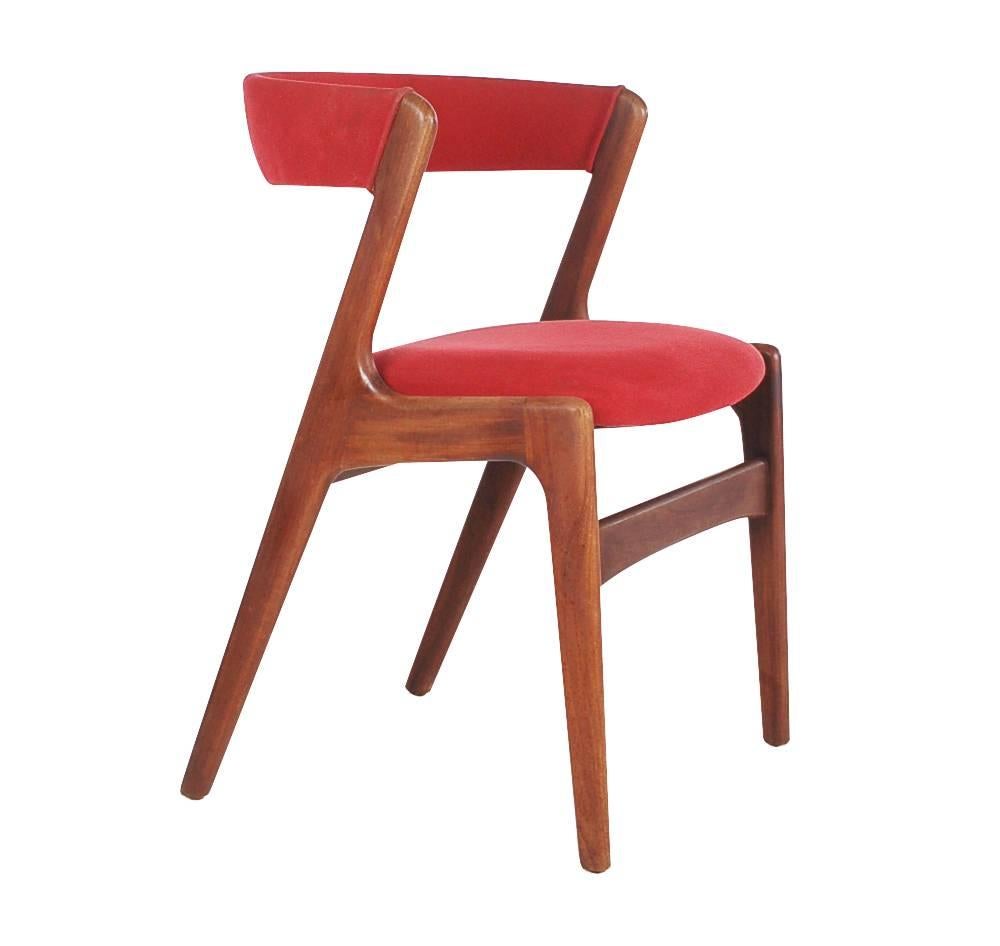 An incredible set of four dining chairs designed by Kai Kristiansen. These feature solid teak frames, signature curved backs, and original upholstery.