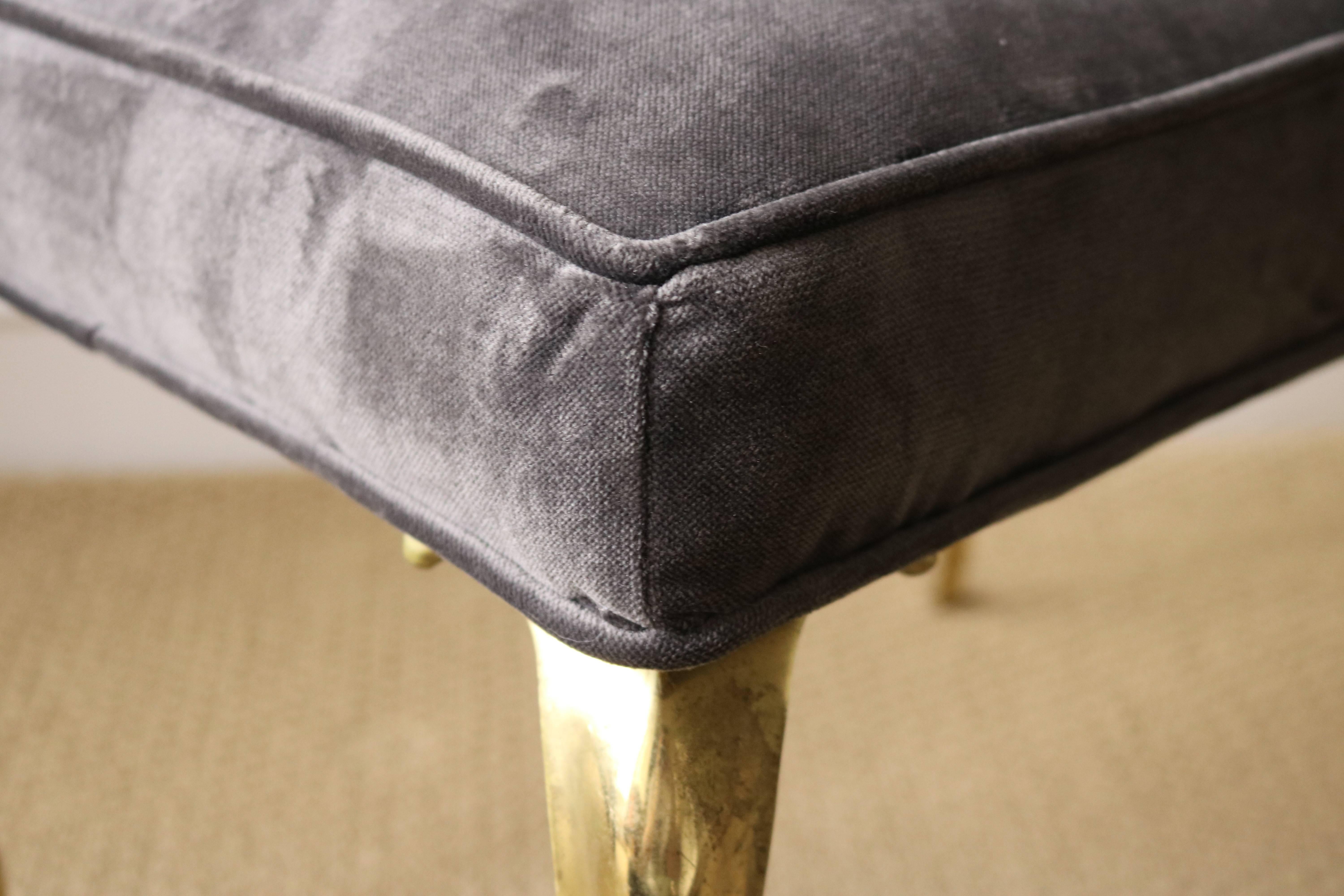 Lovely, sculptural brass legs adorn this lovely ottoman. Freshly upholstered in a luxurious velvet, this lovely piece is sure to add charm to any setting! Brass legs have the patina of age and love.