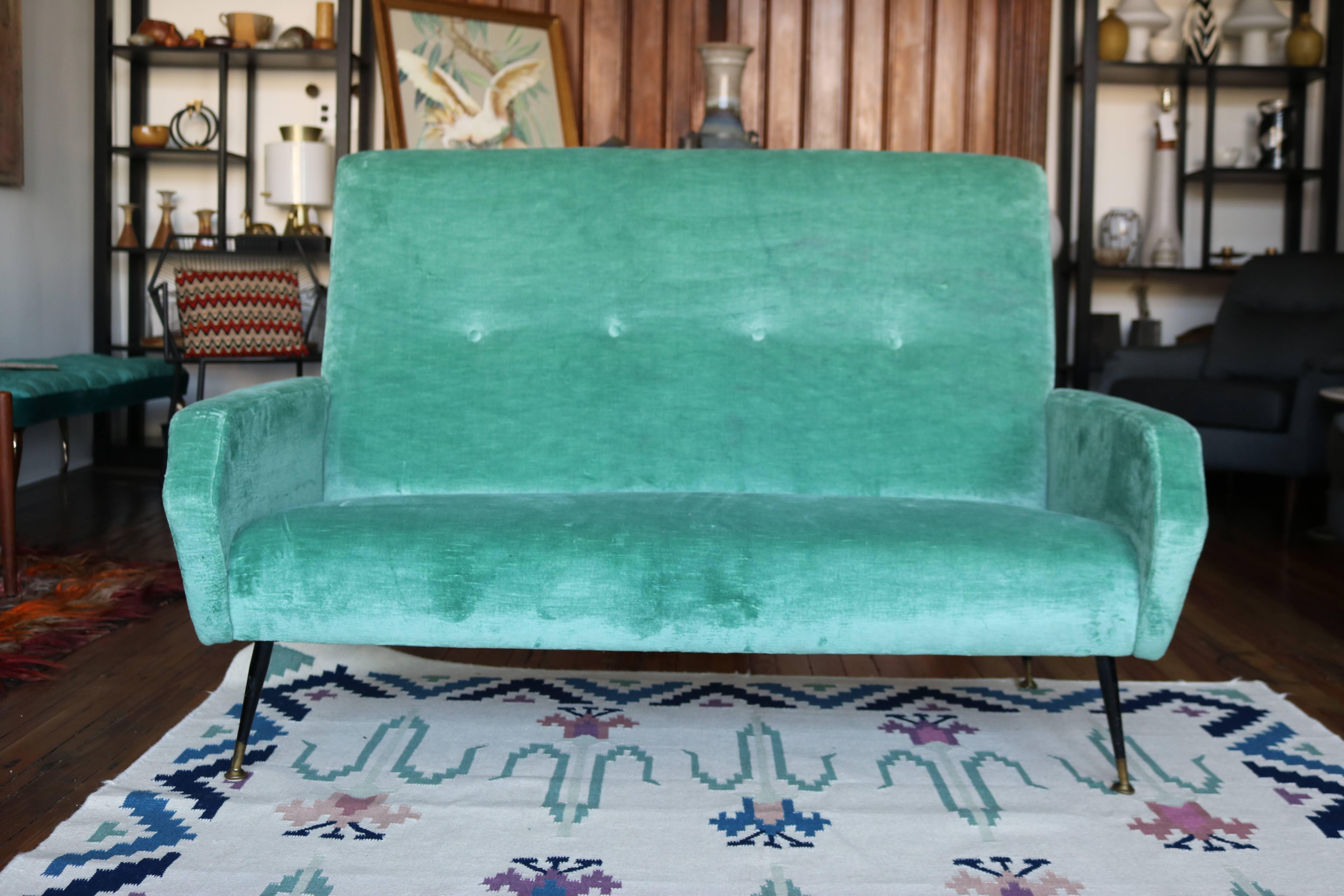 This sleek and lovely sofa was made in Italy in the 1950s. The crushed aqua velvet appears to be original, and while it does show wear (a few thin areas and 