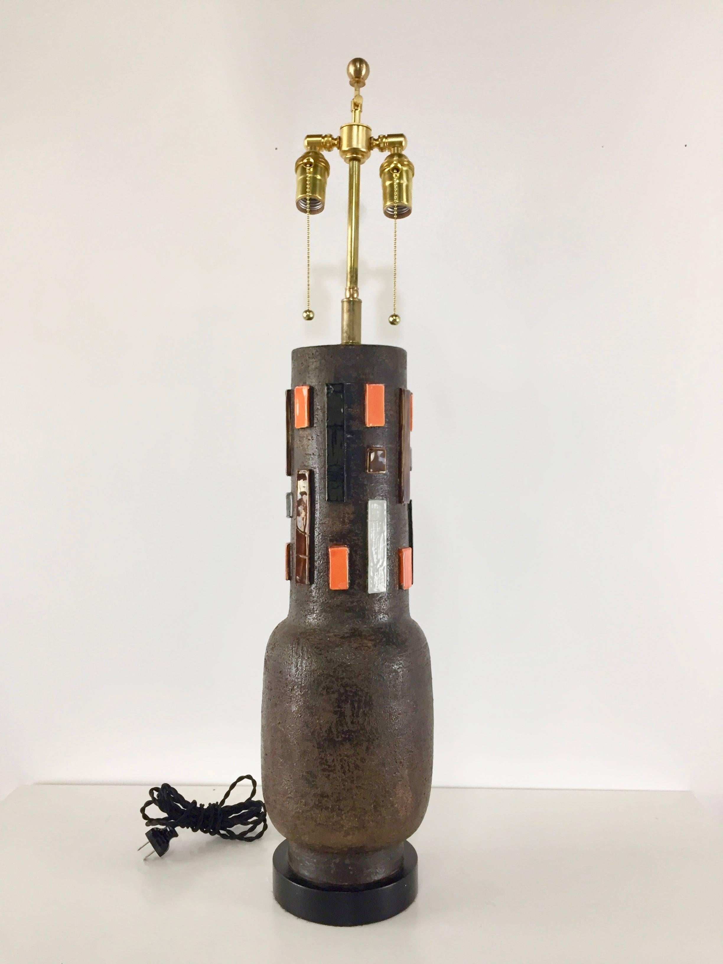 Aldo Londi Bitossi Italian pottery lamp. Long necked pottery element with raised blocks in orange, brown, white and black glaze. This lamp has had a total restoration including new hardware.

Ceramic element is 22" x 7" diameter.