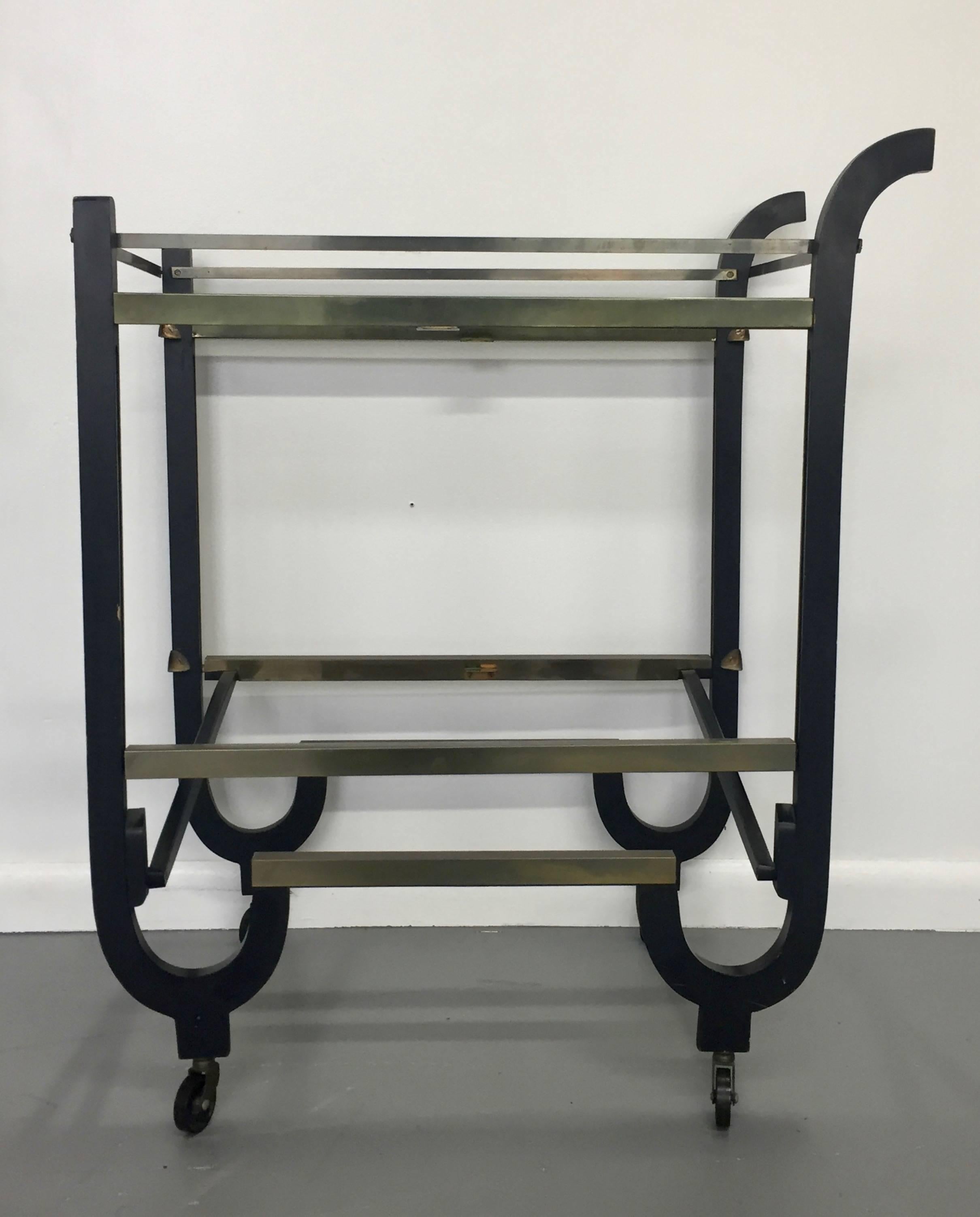Clever Art Deco bar cart that ingeniously folds away. This bar cart has rails and an ebonized wooden frame and of course high Art Deco styling. Attributed to Deskey