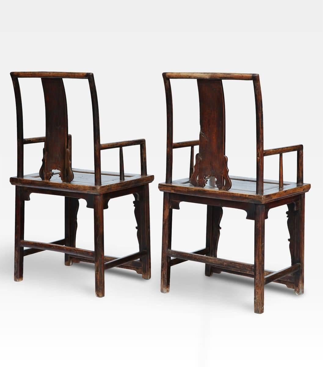 Pair of Chinese chairs made of precious elm wood. The perfect balance between minimal deign and the sinuous lines of the round carved friezes, creating a couple of chairs with an aesthetic impact like no other. The seatback is finely carved and