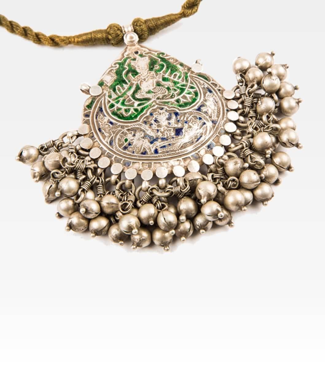 Antique pendant from Himachal Pradesh. The jewel is embossed and depicts Durga, the goddess with multiple arms, the embodiment of the feminine creator energy and owner at the same time of destructive power. The incision is emphasized by green and