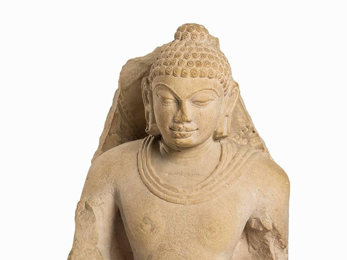 Standing relief figure of a Buddha in samabhanga position.
Meditative facial expression and typically elongated earlobes and small curls.
Plain undergarment, hinted at along the neckline.
The upper garment hinted at though a broad fold extending