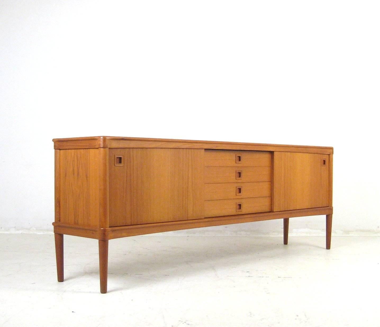 H.W. Klein teak sideboard with two sliding door cabinets each with a shelf.
Four drawers in centre. Signed with stickers. The back of the sideboard is also finished.