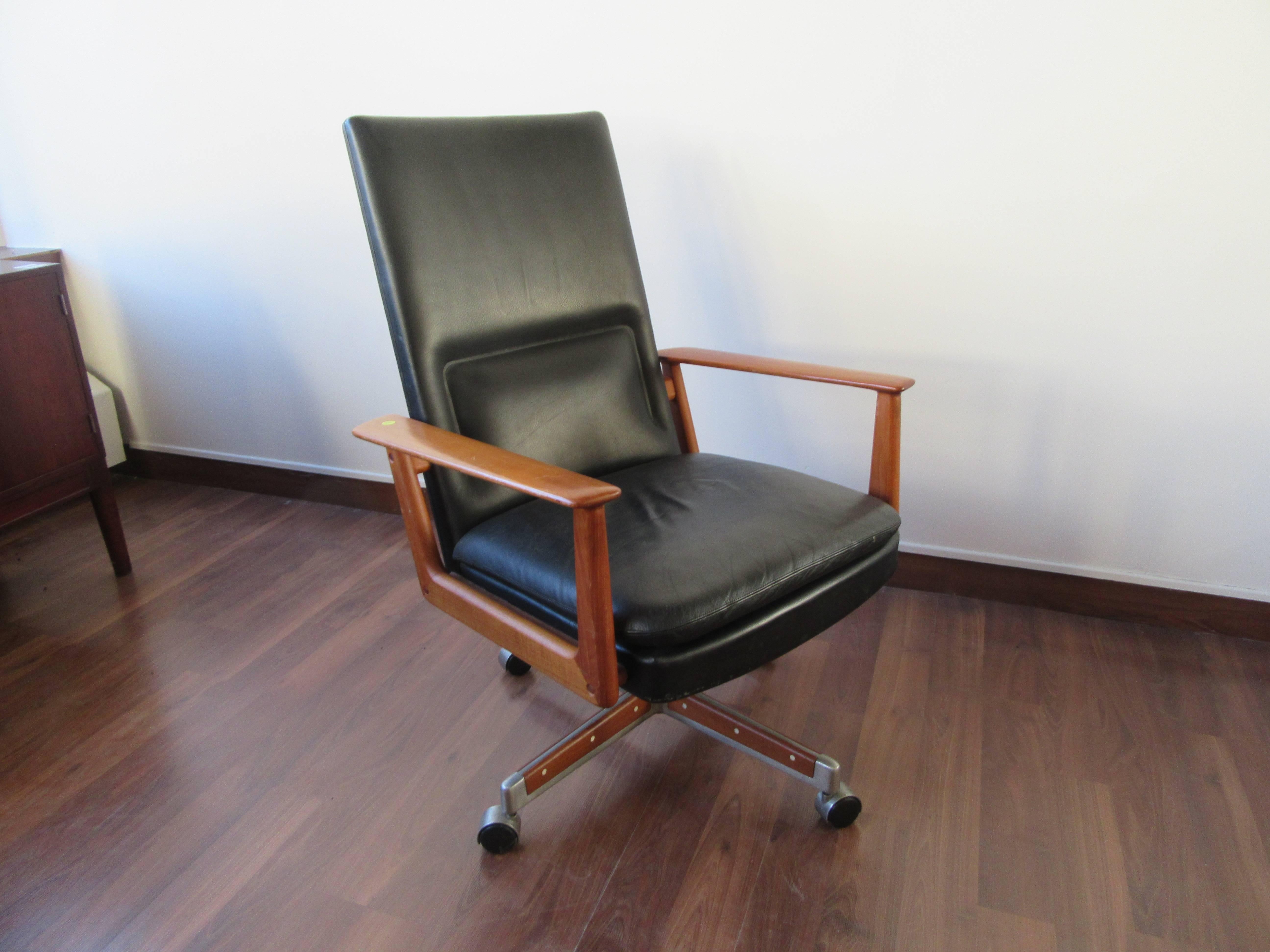 This high backed desk chair is your reward for a job well done. Featuring solid teak arms, the original leather, and an aluminum base with teak inlay, this chair is perfect whether you like to lead from behind or otherwise.