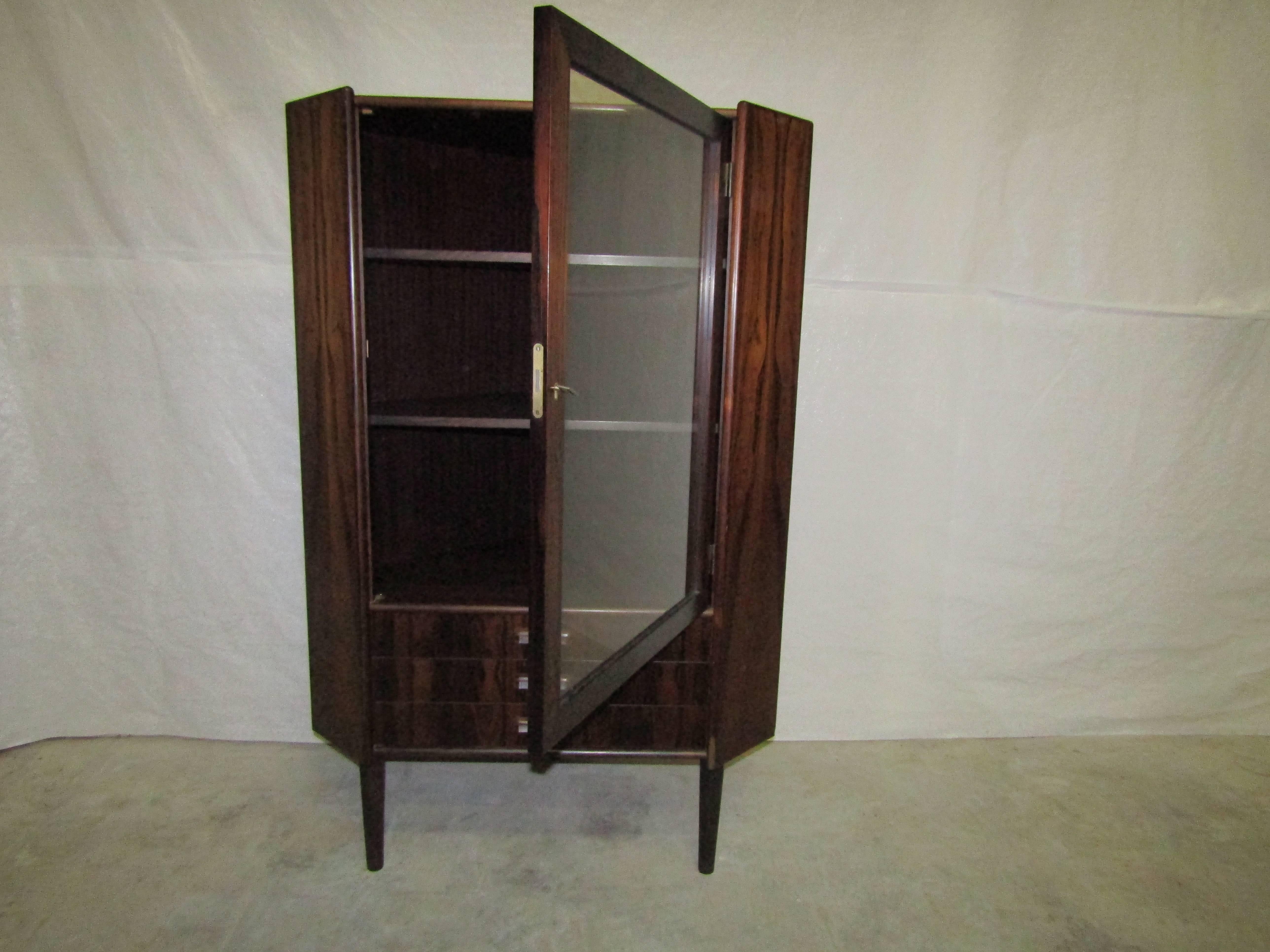Stunning rosewood corner cabinet from Denmark. Featuring glass doors, two shelves and dovetail joints.