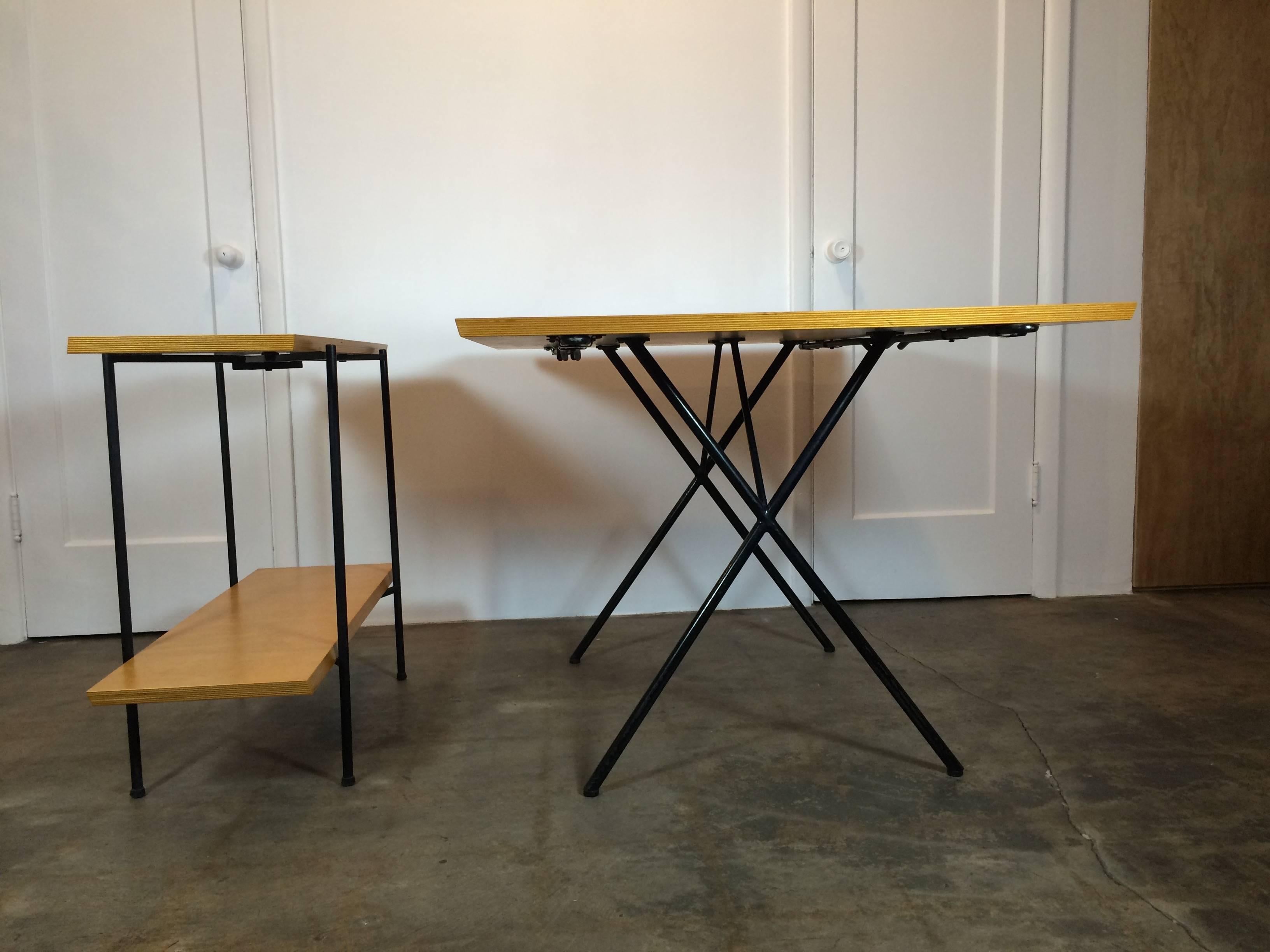 Very rare Tony Paul table and server. The two leaves for the table make up the server, and the frame of the server folds out of the way for storage. Rods underneath the table extend out to support the end leaves. Steel frame, birch top. The frame is