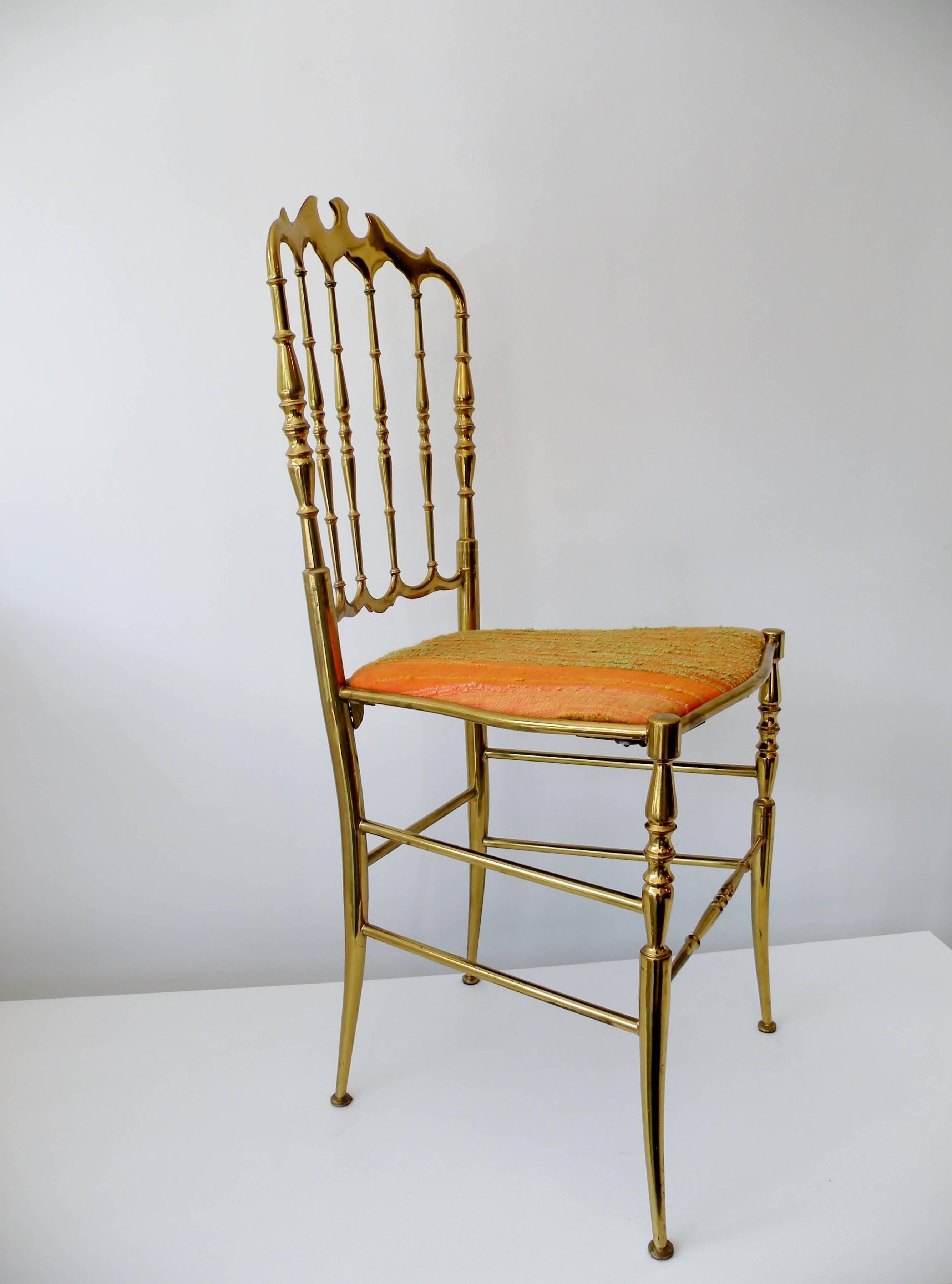 Single 1960s era Italian brass Chiavari side chair. This iconic and elegant design has been a design staple for a century and has today, in its luxurious brass form, become synonymous with Hollywood Regency style. Raw silk upholstered seat in shades