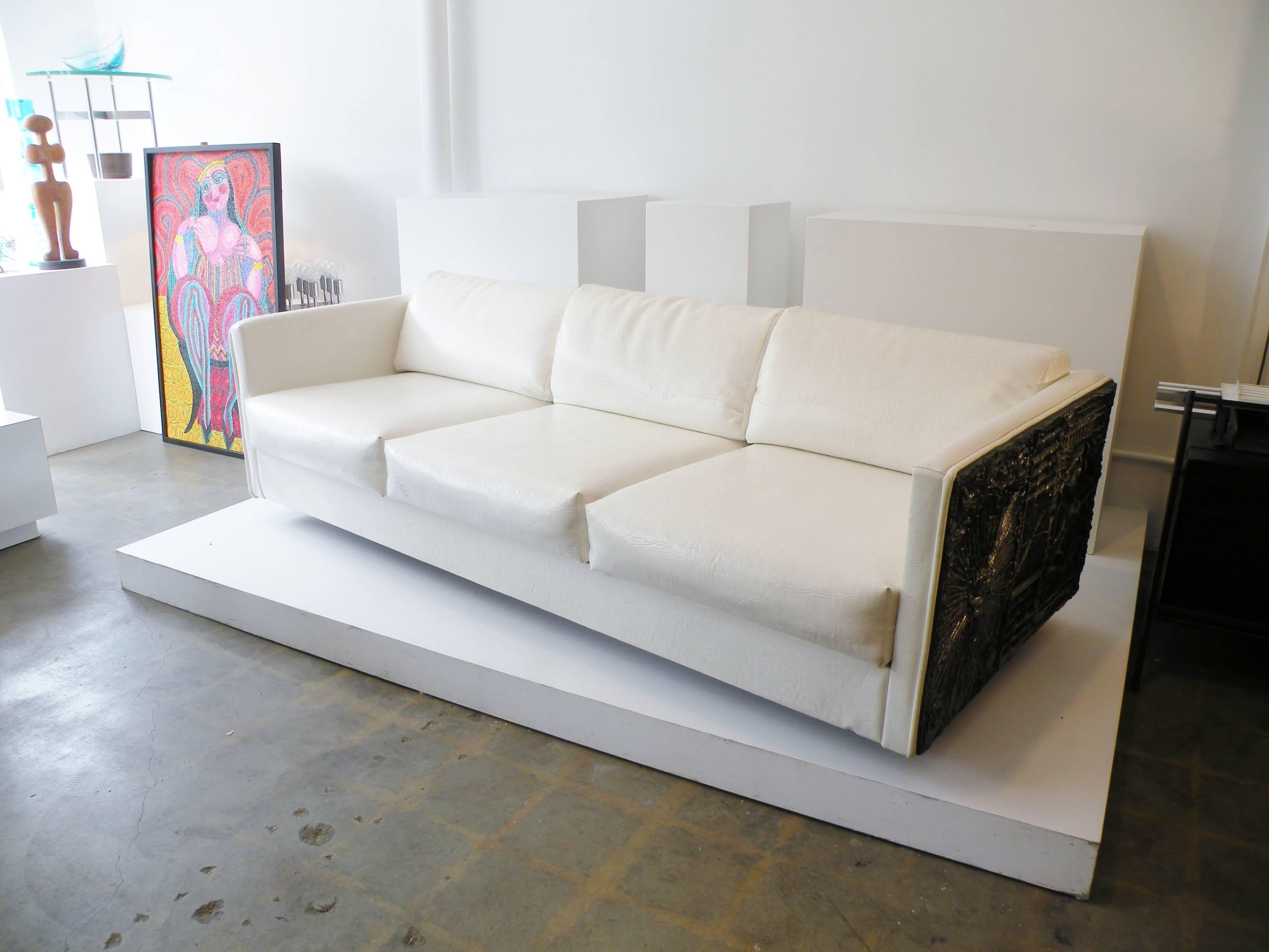 Adrian Pearsall for his Craft Associates Furniture company tuxedo arm three seat sofa. An Brutalist abstract cast panel to each side and upholstered back. With original man made off-white textured leather upholstery.