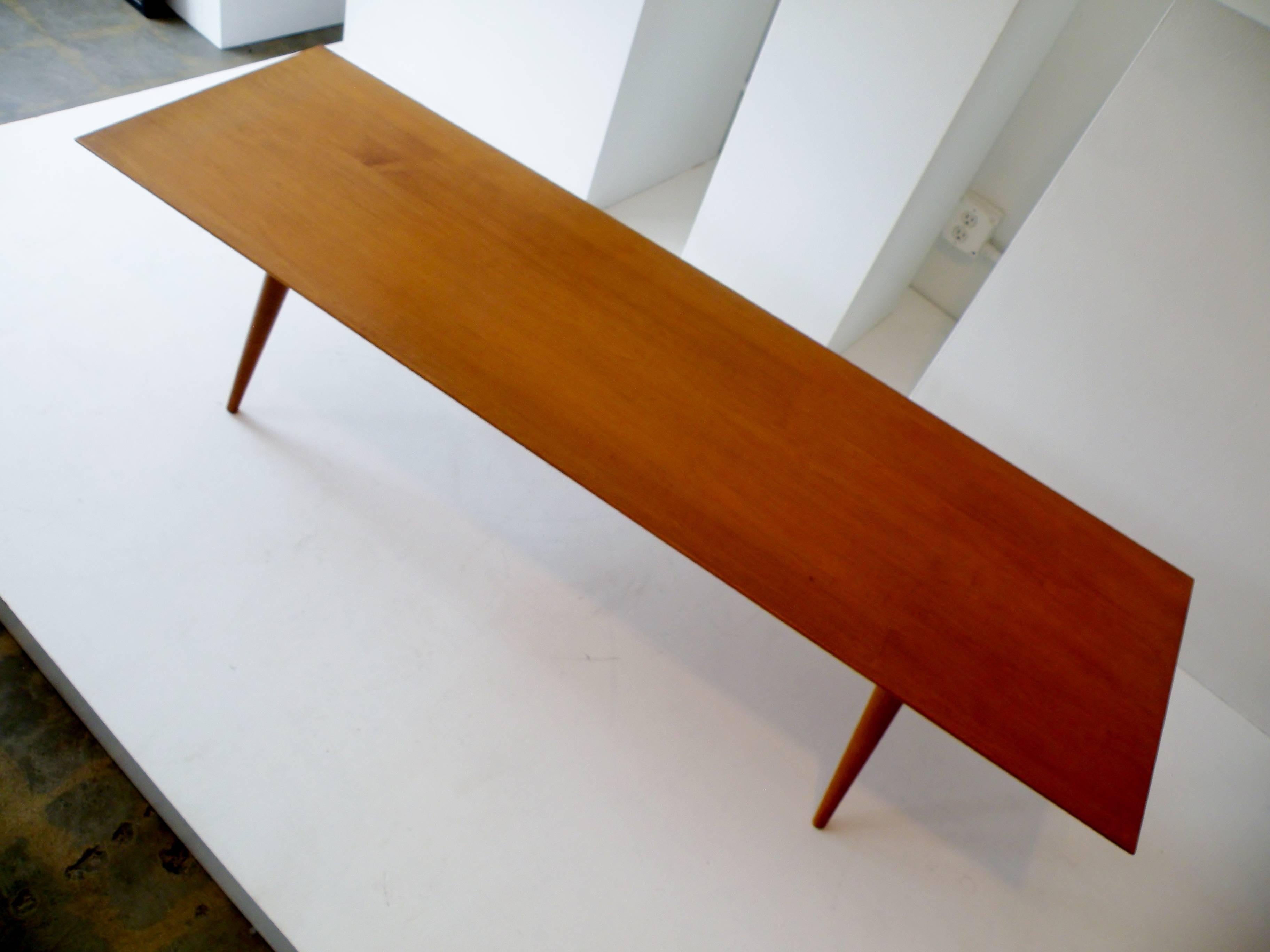 Paul McCobb designed rectangular coffee table or the bench for cabinet separates, of solid maple with tapered legs and manufactured by the Winchendon Furniture Company.