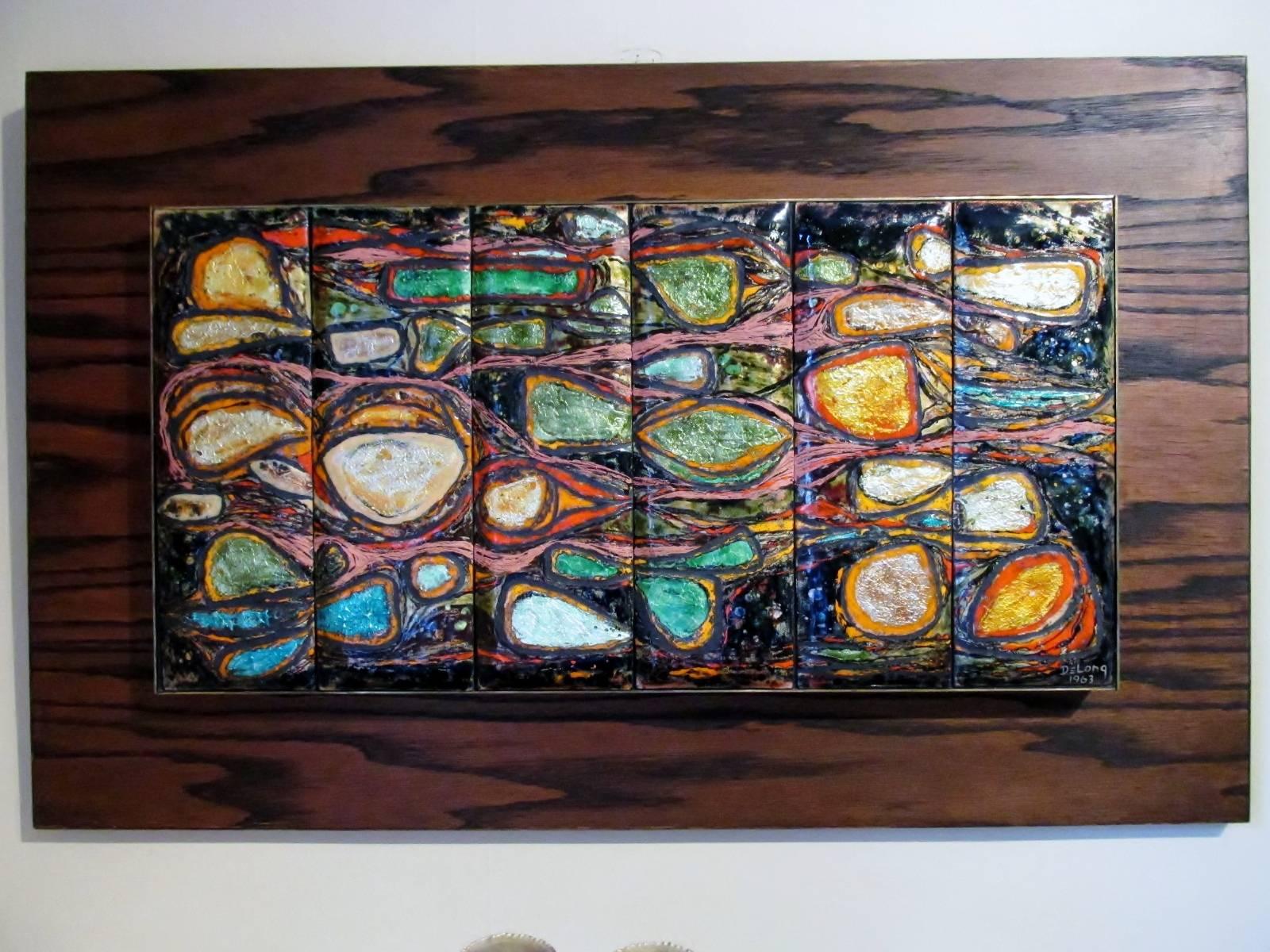 Dated 1963, a modernist enamel wall plaque from renowned artisan Barbara DeLong. Titled “Conglomerate”, measure: 24” x 12” enamel on copper tiles with brass surround on a 32” x 20” plywood walnut backing. DeLong, renowned in Denver, Colorado for her