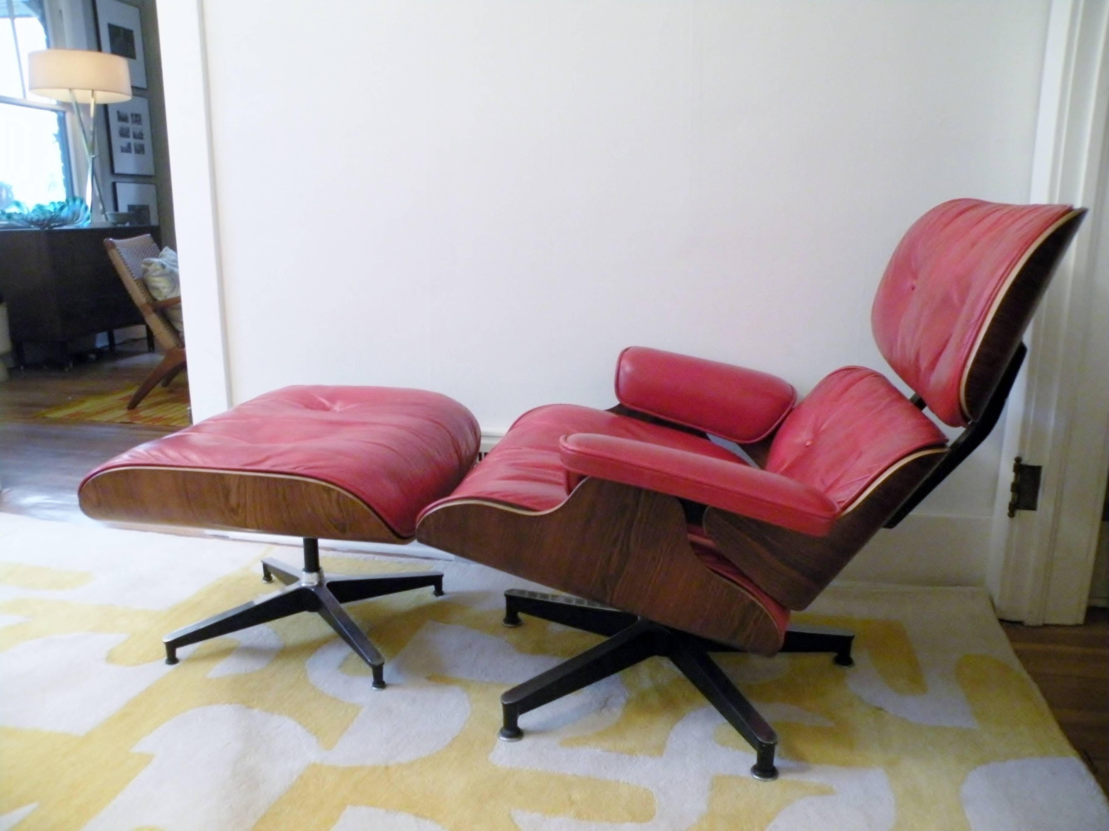 An important 1960s custom order Charles & Ray Eames Herman Miller 670/671 lounge chair with matching ottoman with lipstick red leather and rosewood shells. Chair measures 32" high, 34" wide, and 35" deep, ottoman 17" high,