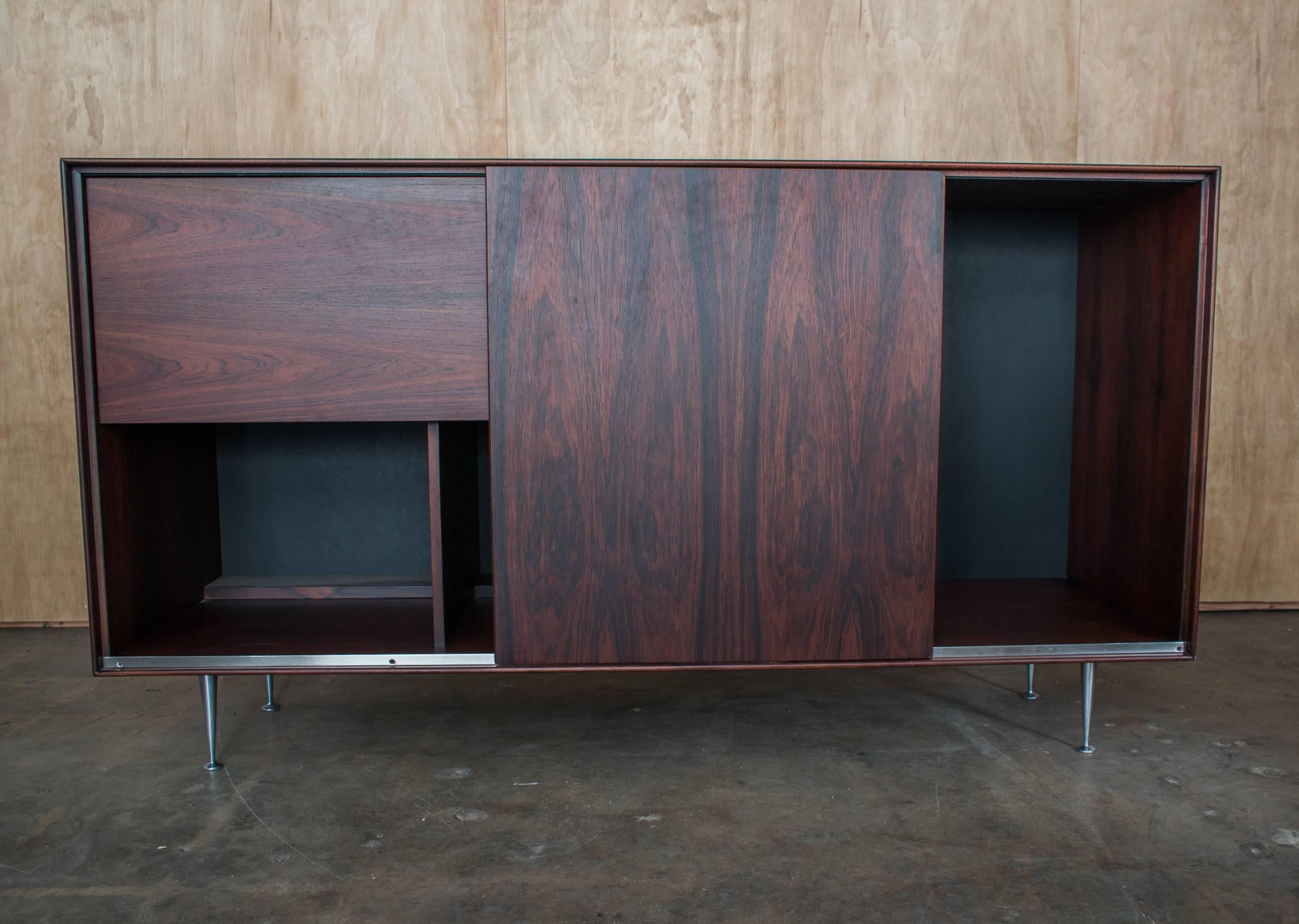 Late 1960s Herman Miller rosewood thin edge sideboard designed by George Nelson & Assoc. Sliding panel opens to reveal storage with drop down door reveling dry bar bottle and glassware storage. Aluminum legs.