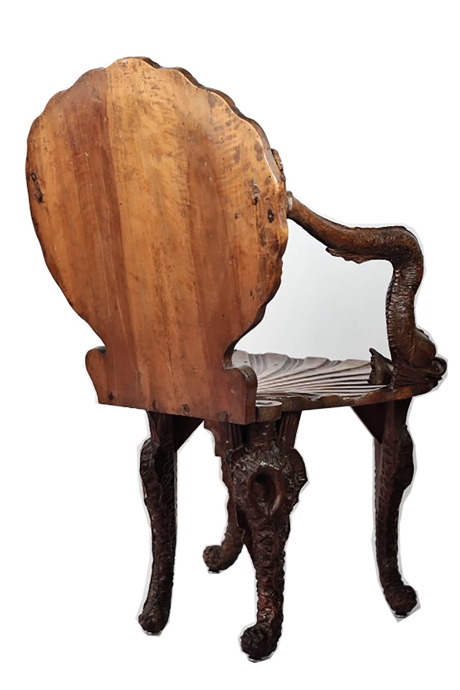 Ornate walnut grotto chair with carved dolphin arms and shell back. 

