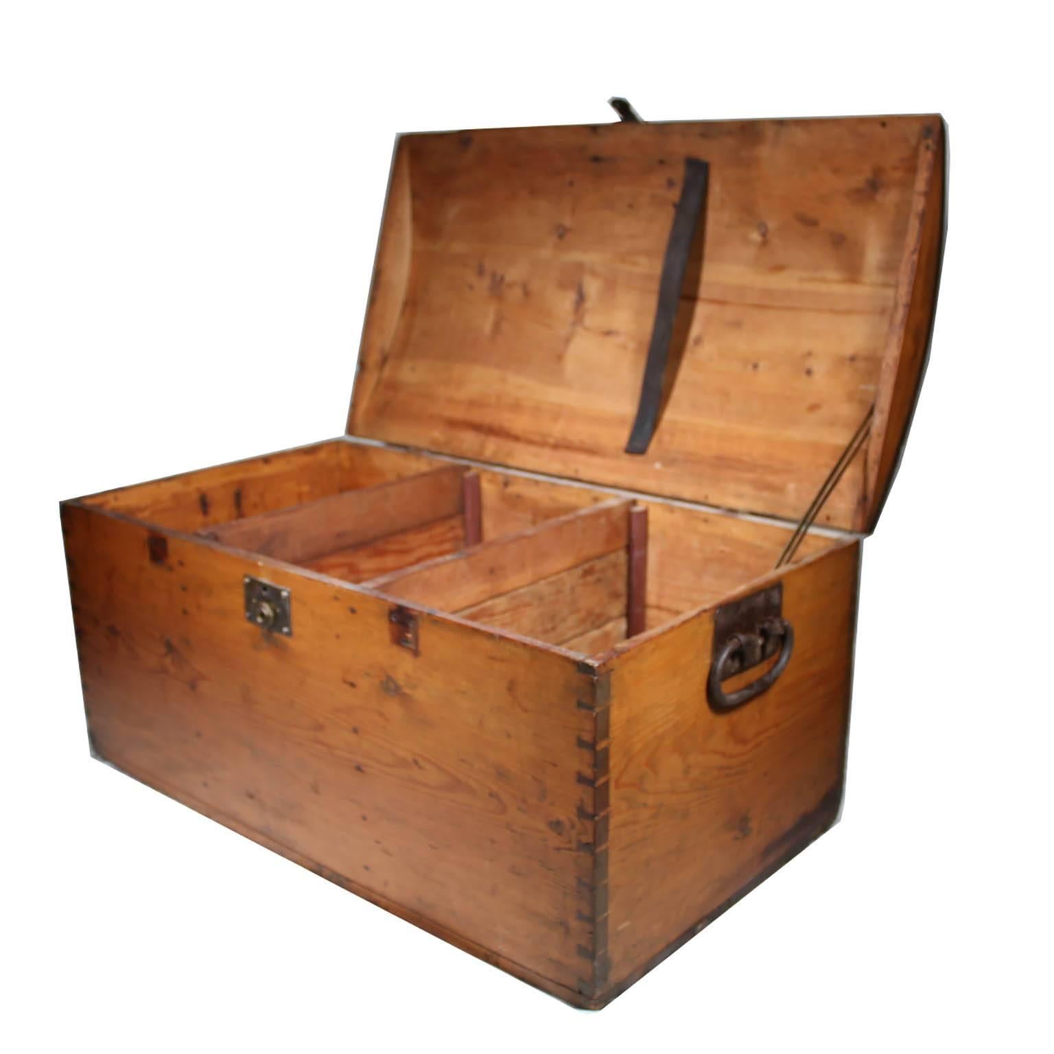 Wooden trunk with cast iron handles and latch. The interior has three vertically separated sections and a leather strap on the lid.