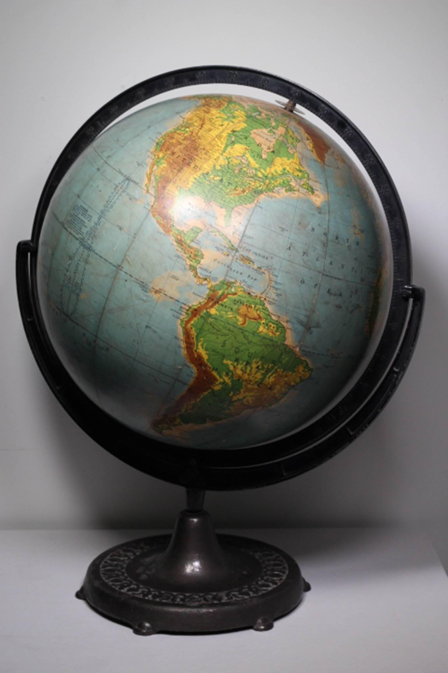 Monumental Rand McNally globe with a cast iron base and bracket. The globe rotates on the bracket. The globe appears to be either glass or metal under the paper map covering.