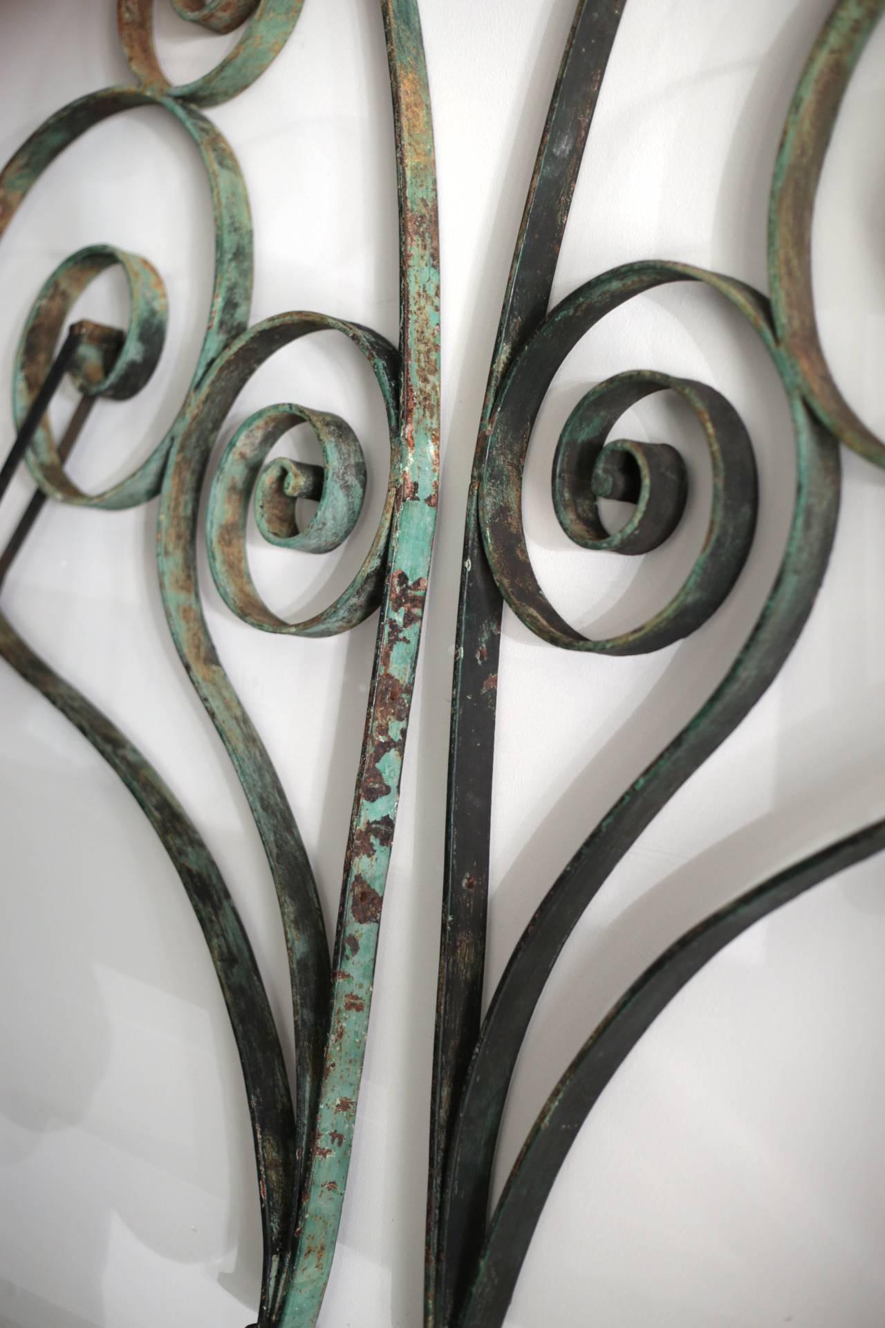 A pair of distressed green steel French awing brackets. The metal is intact with screw holes and a metal bar to attach the awning.
