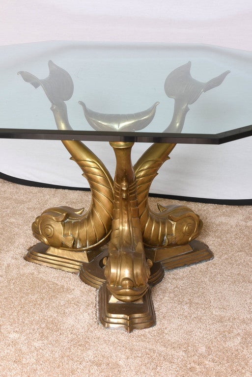 This amazing cast-bronze dining table with its three stylized dolphins with upturned tail-fins takes its inspiration from pieces in Venetian palazzos, English Regency drawing rooms and stylish creations by Tony Duquette.

The glass is 3/4