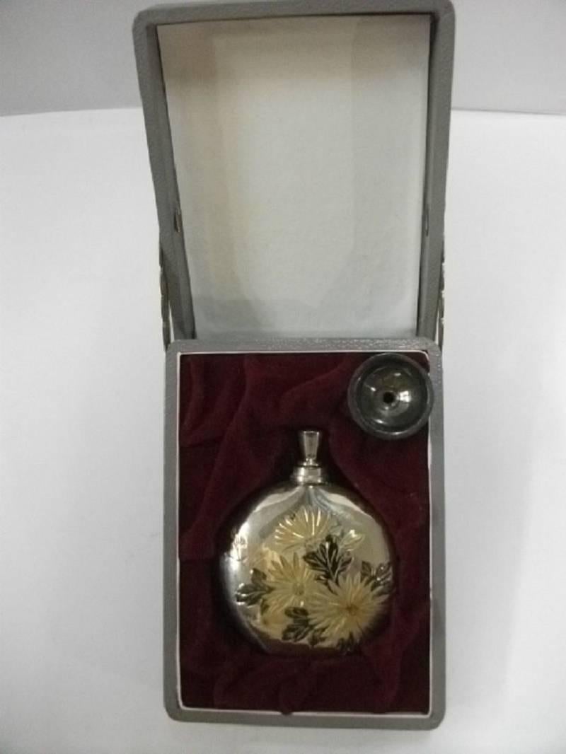 Japanese Imperial Chrysanthemum flower perfume bottle executed in pure.950 silver with gold gilding and original presentation box.

This lovely perfume bottle features a spray of royal chrysanthemum flowers with gold gilt features and includes a