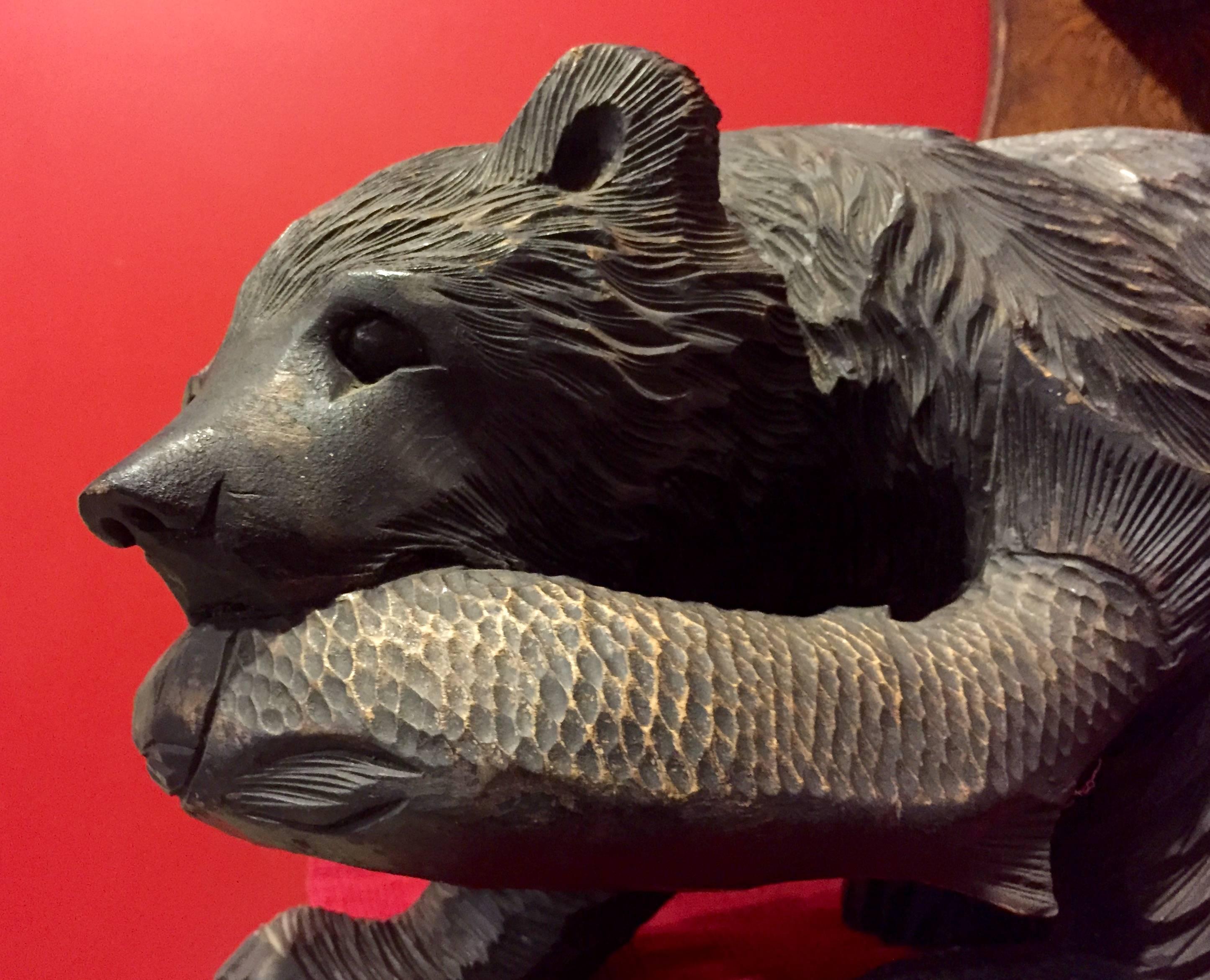 Japan, fine old medium scale carving of a bear, Higuma, grasping a salmon fish, carved by the Ainu people of Northern Japan (Hokkaido Island). Carved Ittobori style (from one wooden piece) of cryptomeria or cedar wood. Mid-Century, dating to
