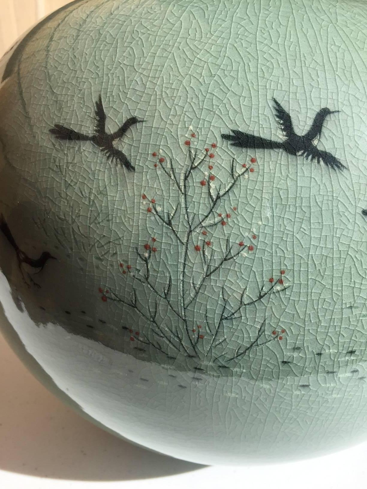 Signed, Mint and Boxed

Korea, a fine and beautiful bluish green ceramic vessel depicting - birds in flight - among cherry blossoms, with signed box, mid to late 20th century, 

Dimensions: 11 inches high and 14 inches diameter. Excellent crackled