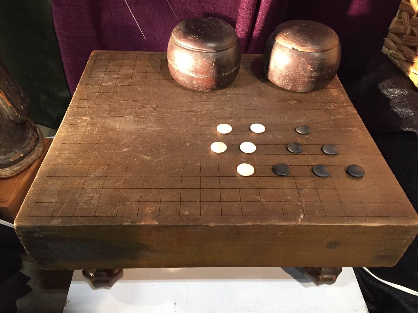 This is a scarce and fun Japanese thick, antique wooden goban “GO” board, 1920s-1930s, handcrafted of Kaya wood, 8” H x 20” W, and with a warm aged patina. It comes complete with the GO ishi stones and wood 