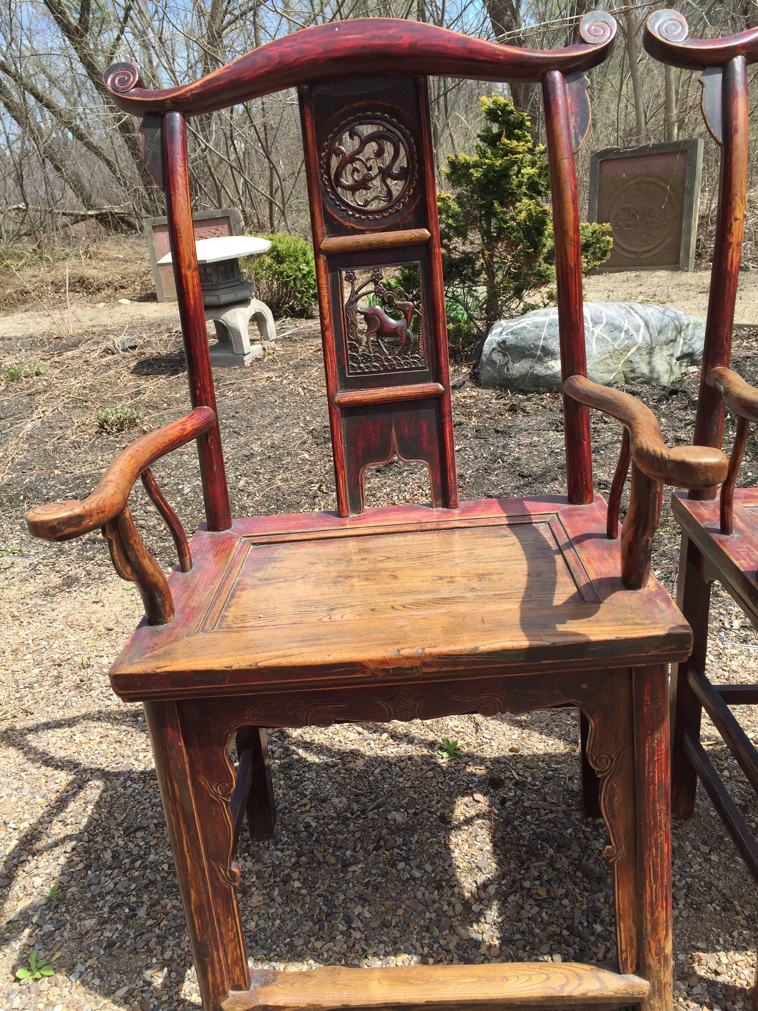 China, a lovely and solid pair of hardwood elm humu scholar chairs with original traces of red lacquer. Handsome look, generous seating area, appealing examples.

Back splat depicts three cameos of deer, frolicking dragons, and censer or pagoda