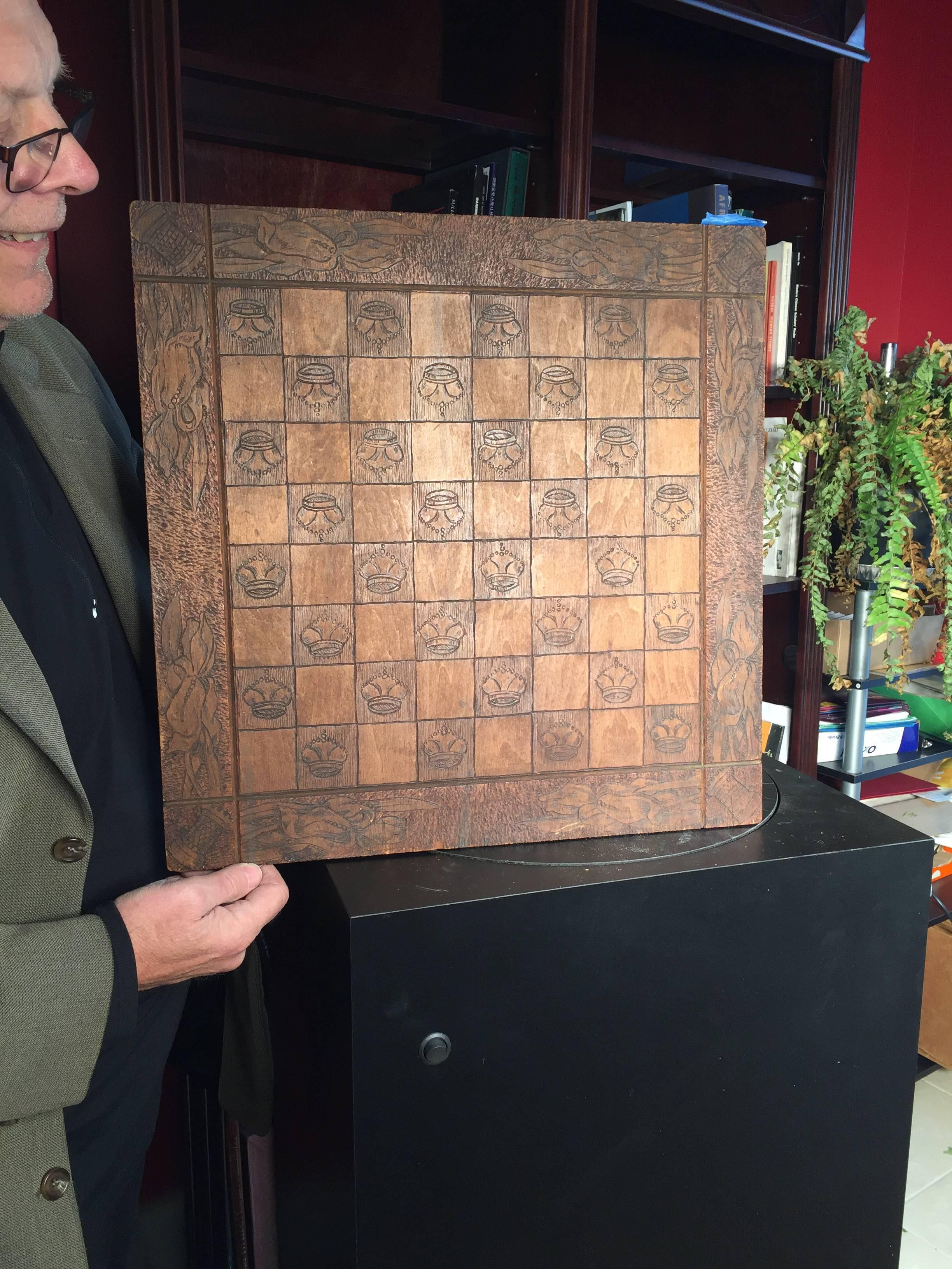 This is a beautiful 18 inch square old wooden Folk Art game board, hand incised in great detail with images of crowns and floral boarders, signed in wood burned pyrography verso F.W.C. '09. and with an original label remnant still