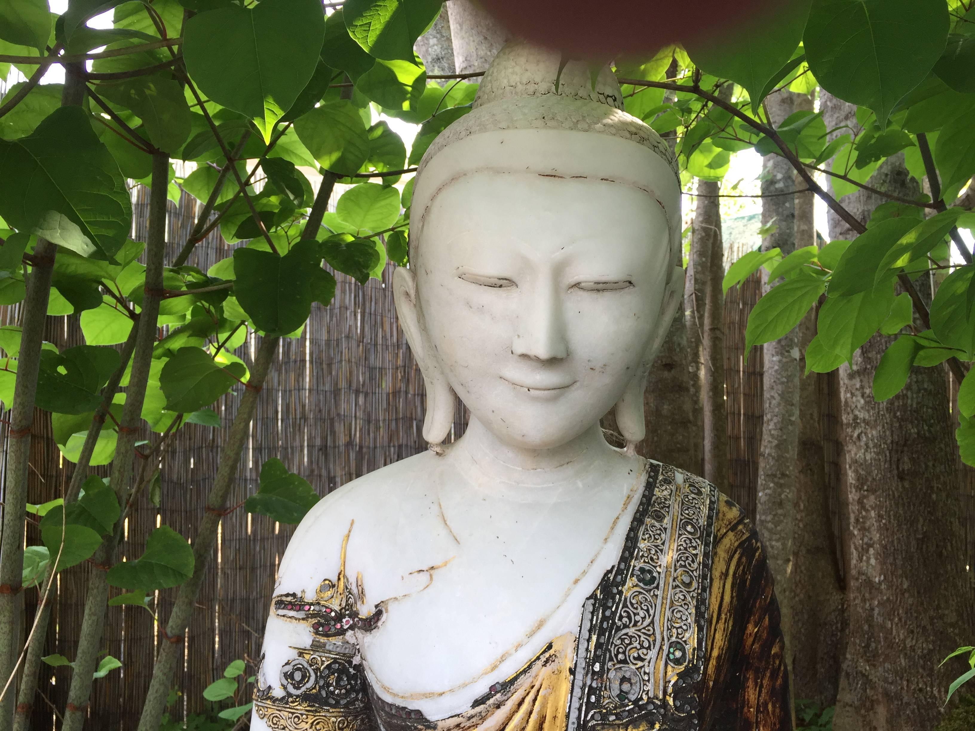 Burma, Mandalay, a monumental hand carved and hand lacquered stone seated Buddha with a joyful face dating to the early 20th century.

The monumental  effigy of the Buddha with realistic and joyful face and hand carved of alabaster embellished with