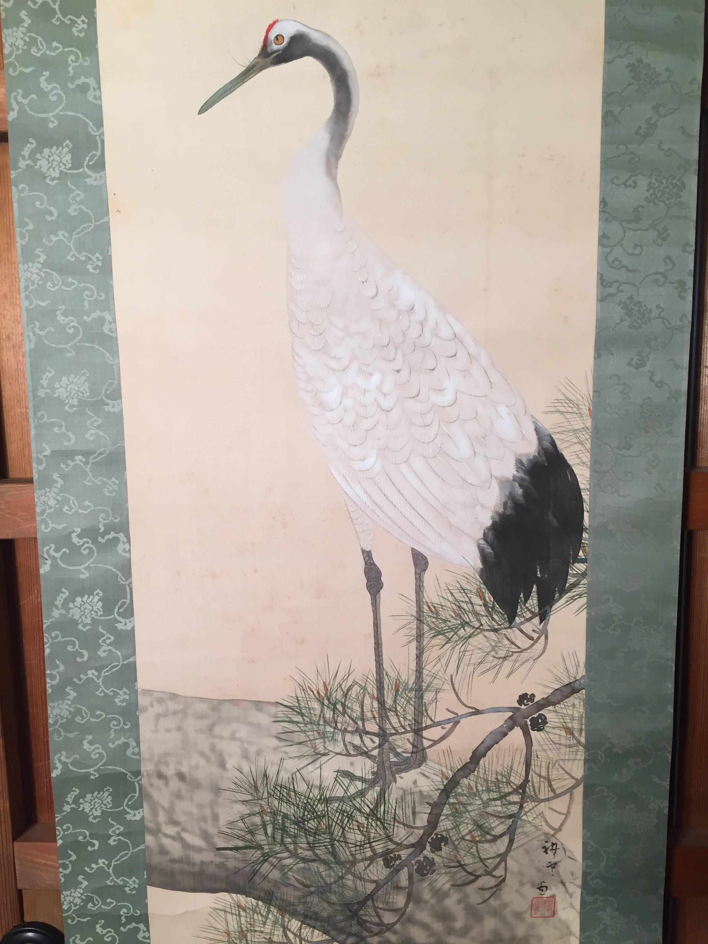 Japan, an adroit red-crowned crane stands erect as if stalking game loosely camouflaged by the branches of a pine. This auspicious artistic combination from Japan is hand-painted on silk in scroll form and dates to the 1940 early Showa era. It's