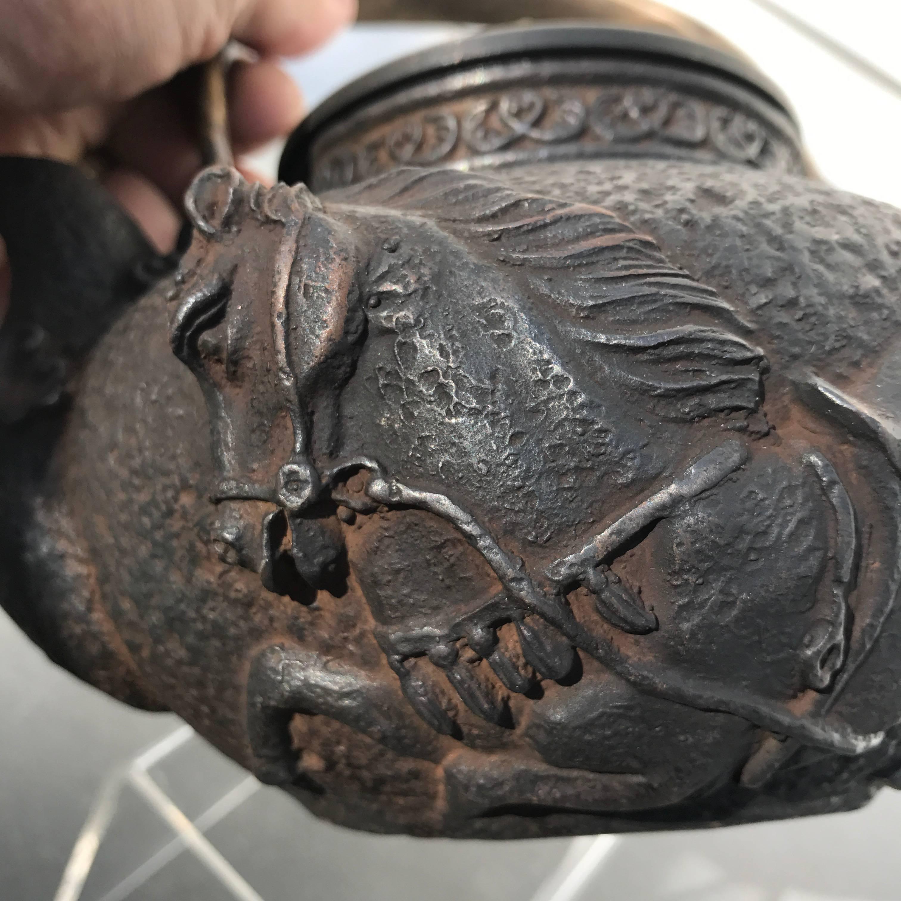 Here's a finely cast traditional iron teapot -tetsubin- with a deep relief samurai horse carving- an unusual and fine treasure from Japan. 

Immediately usable.

Beautiful deep relief with highly detailed handle.

This was sourced from a large