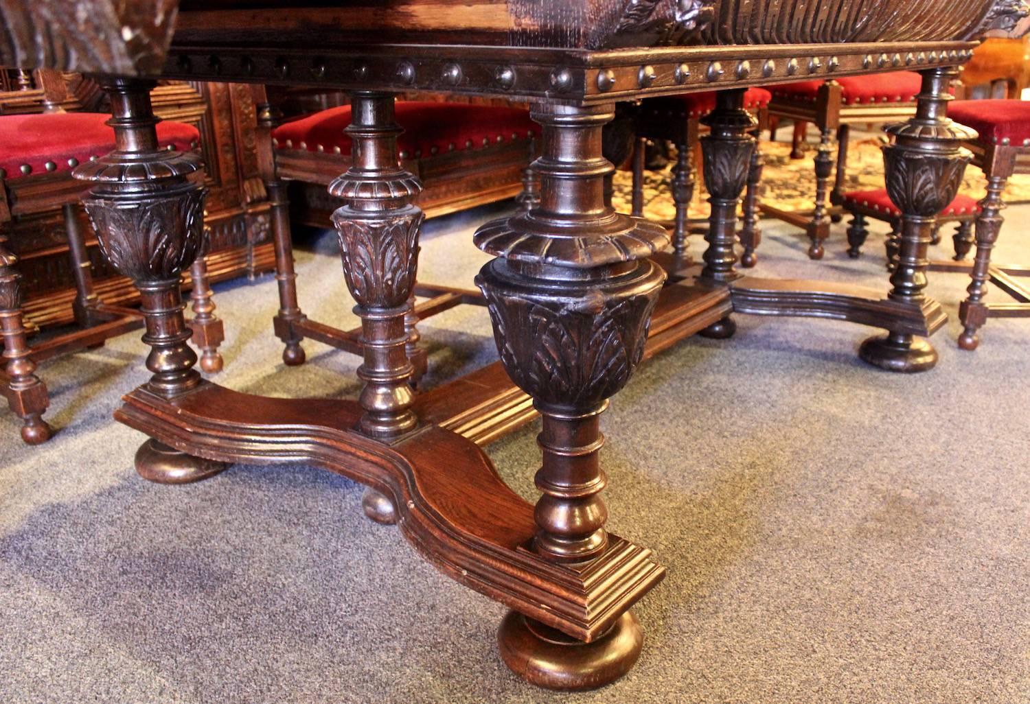 This ornately carved Renaissance style dining set includes an extendable table with two leaves, six standard chairs, two-arm chairs, two foot stools and two buffets. The chairs feature top metal handles and raised studs. The storage on the two