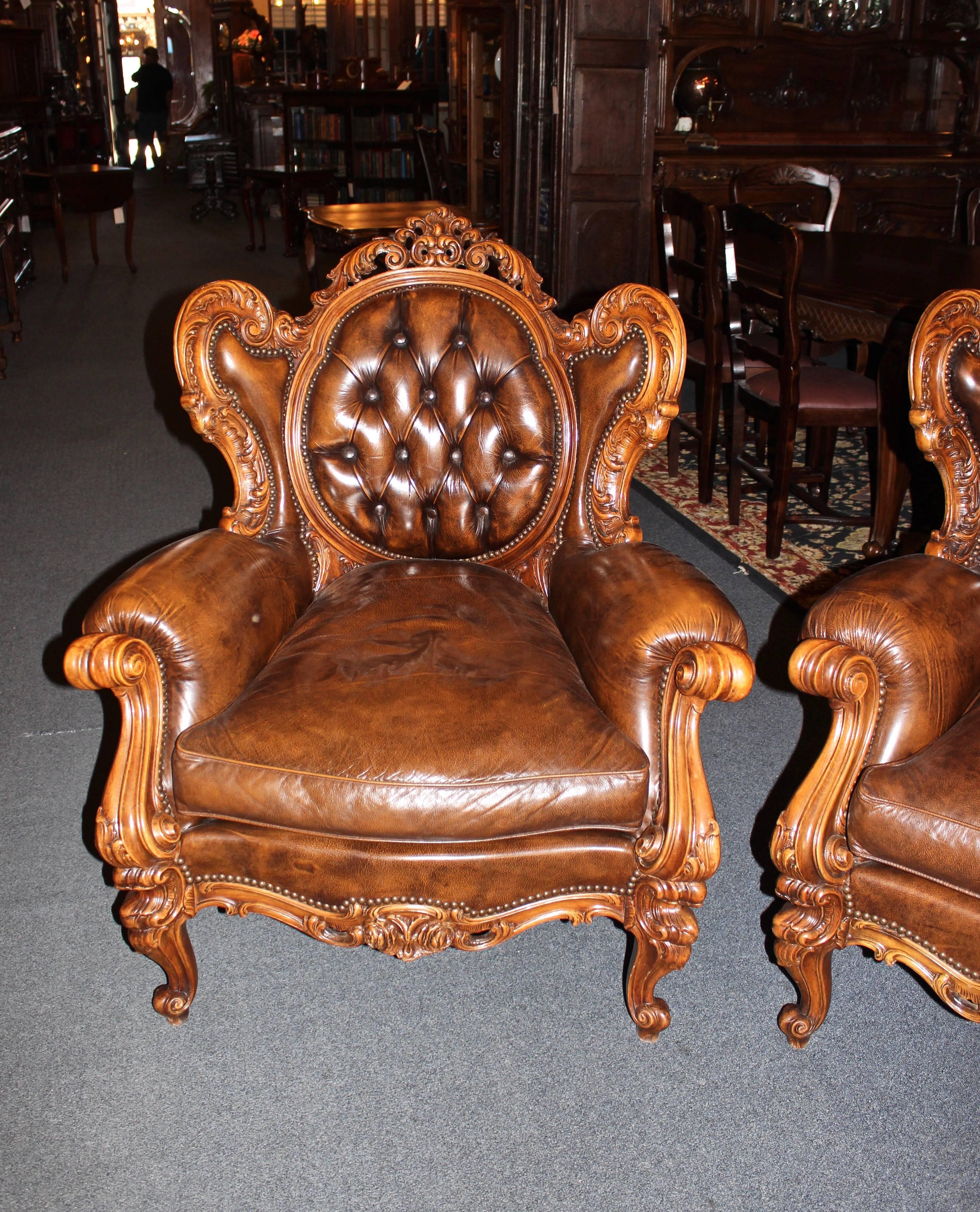 This 20th century French parlour set is made in the Rococo style and includes one sofa and two side chairs. Features gorgeously hand-carved walnut and the original tufted leather. Upholstery stud accents. Sofa measures approximate 38" D x
