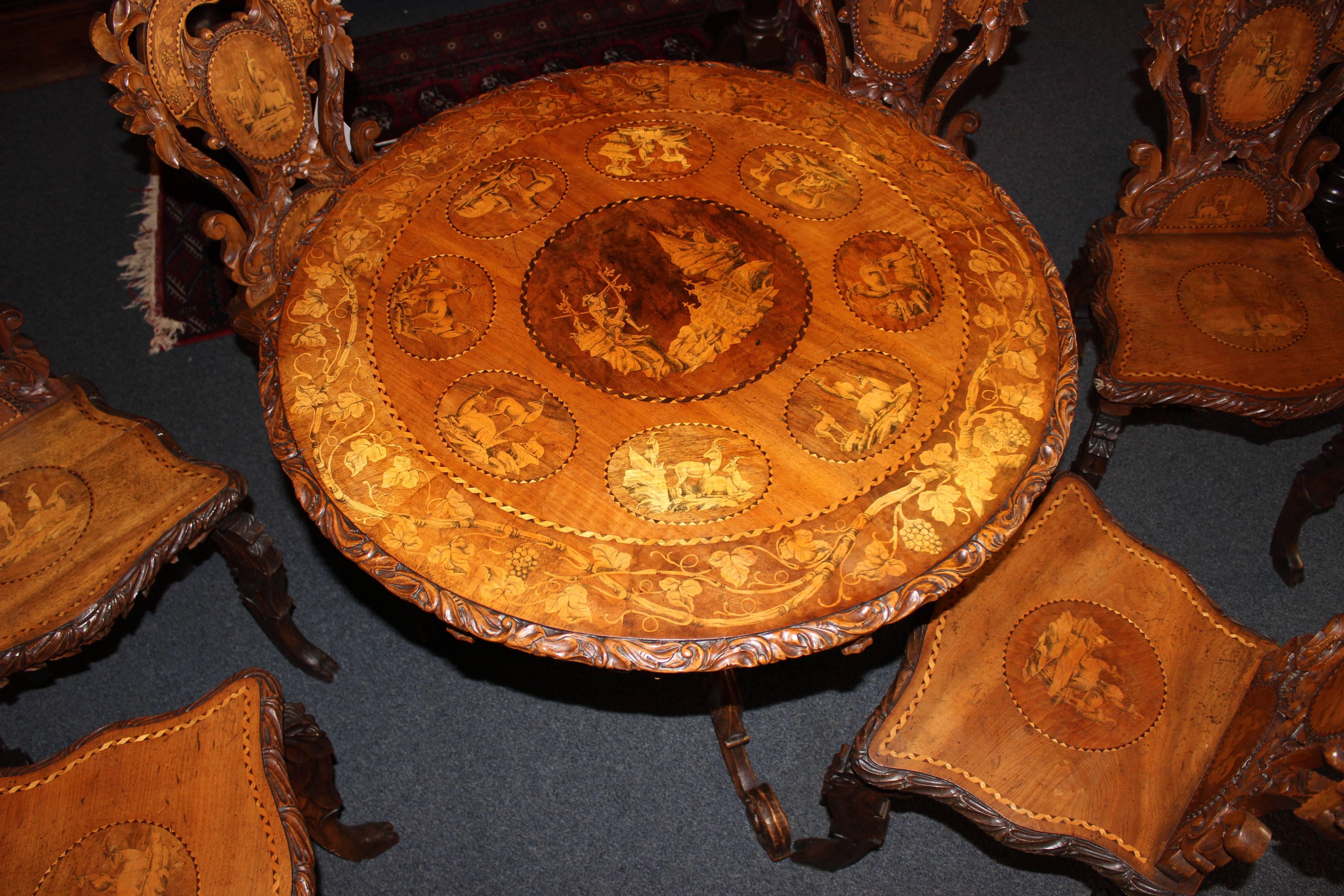 This early 20th century black forest style table used to be carried outside for picnics. Comes with the one foldable table and six chairs that can be taken apart. Features multiple unique and ornate inlaid scenes as well as beautifully carved