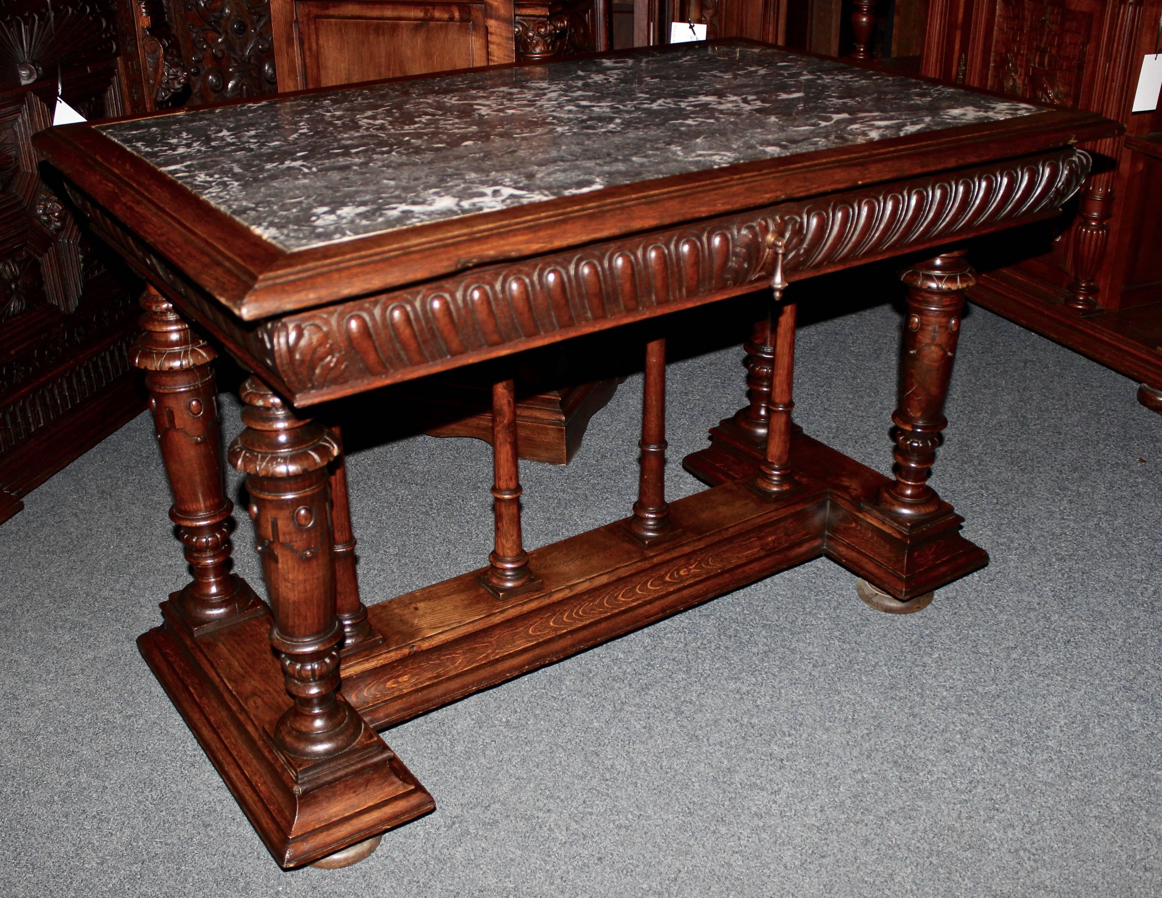 This French walnut table is hand-carved with ornate detail around its sides and on the legs.  It is topped with a gorgeous piece of gray and white marble.  Storage includes one large pull-out drawer.