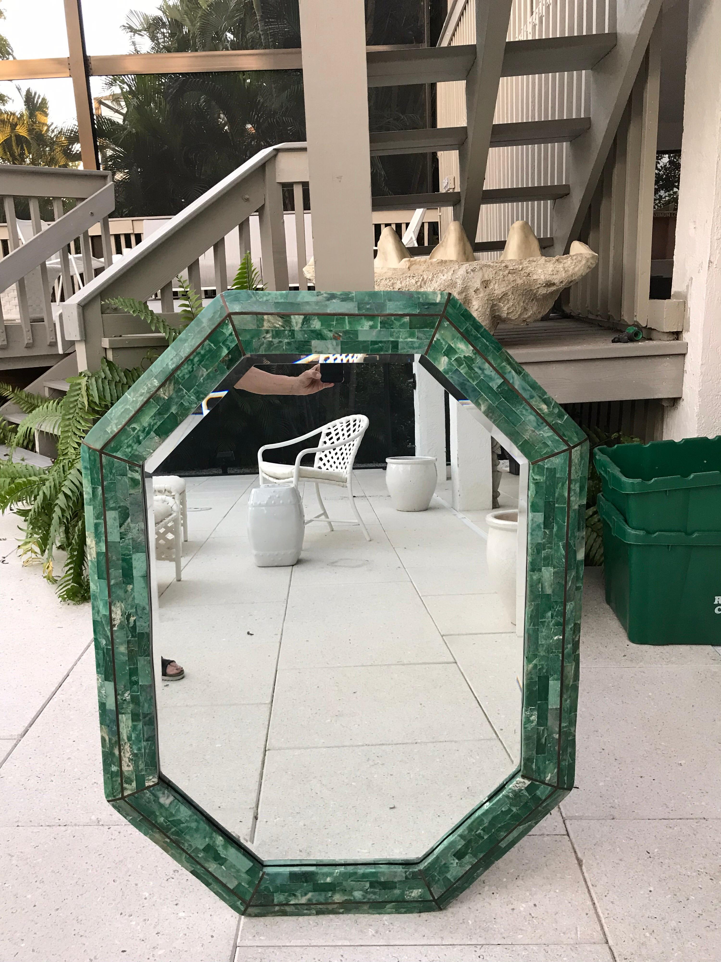 This is a octagonal tessellated malachite colored stone mirror with brass inlays The mirror was designed by Robert Marcius for Maitland-Smith in 1984-1986.
