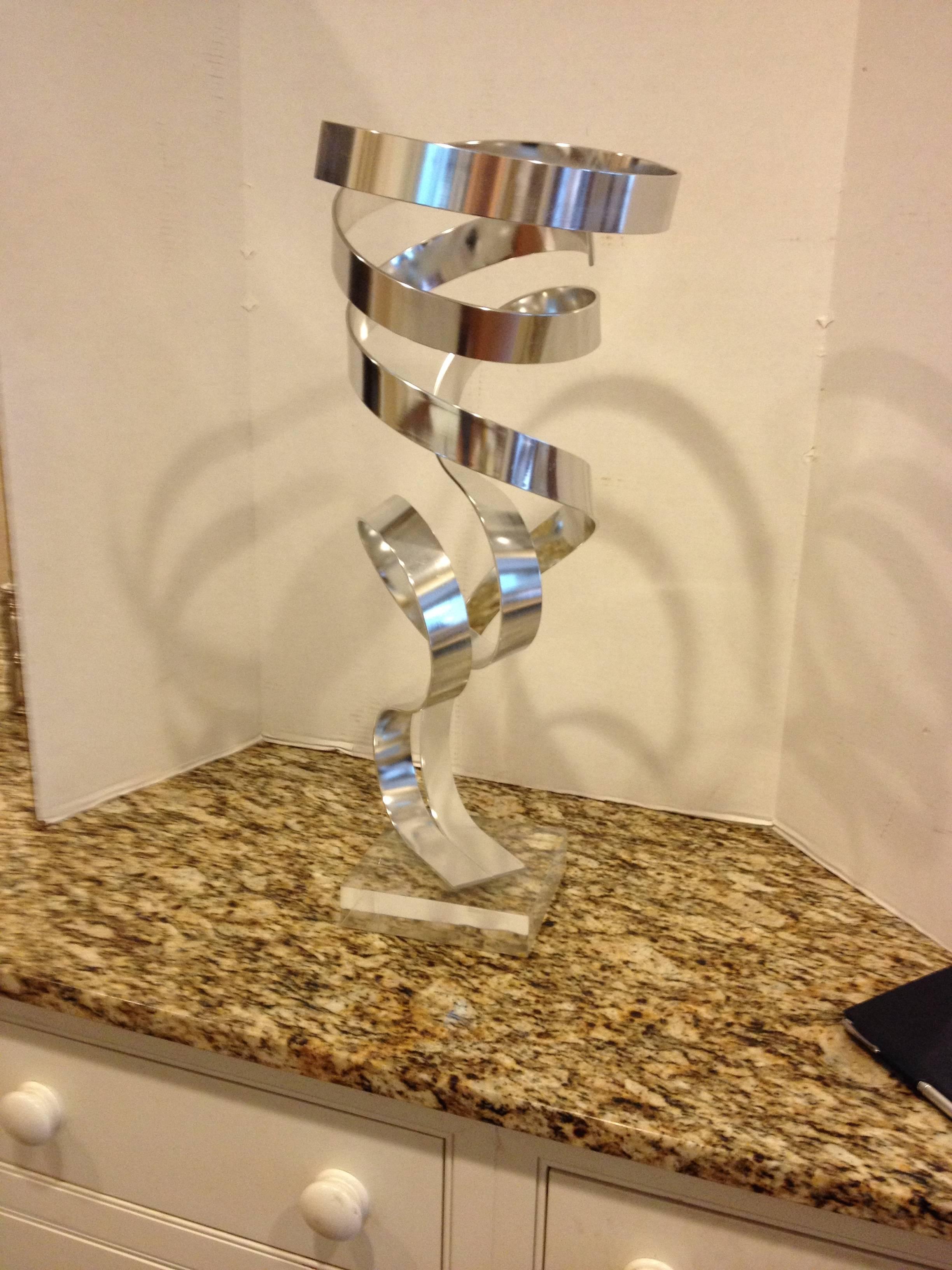 A Dan Murphy anodized aluminum double ribbon sculpture on a 6.75 x 6.75 lucite base.