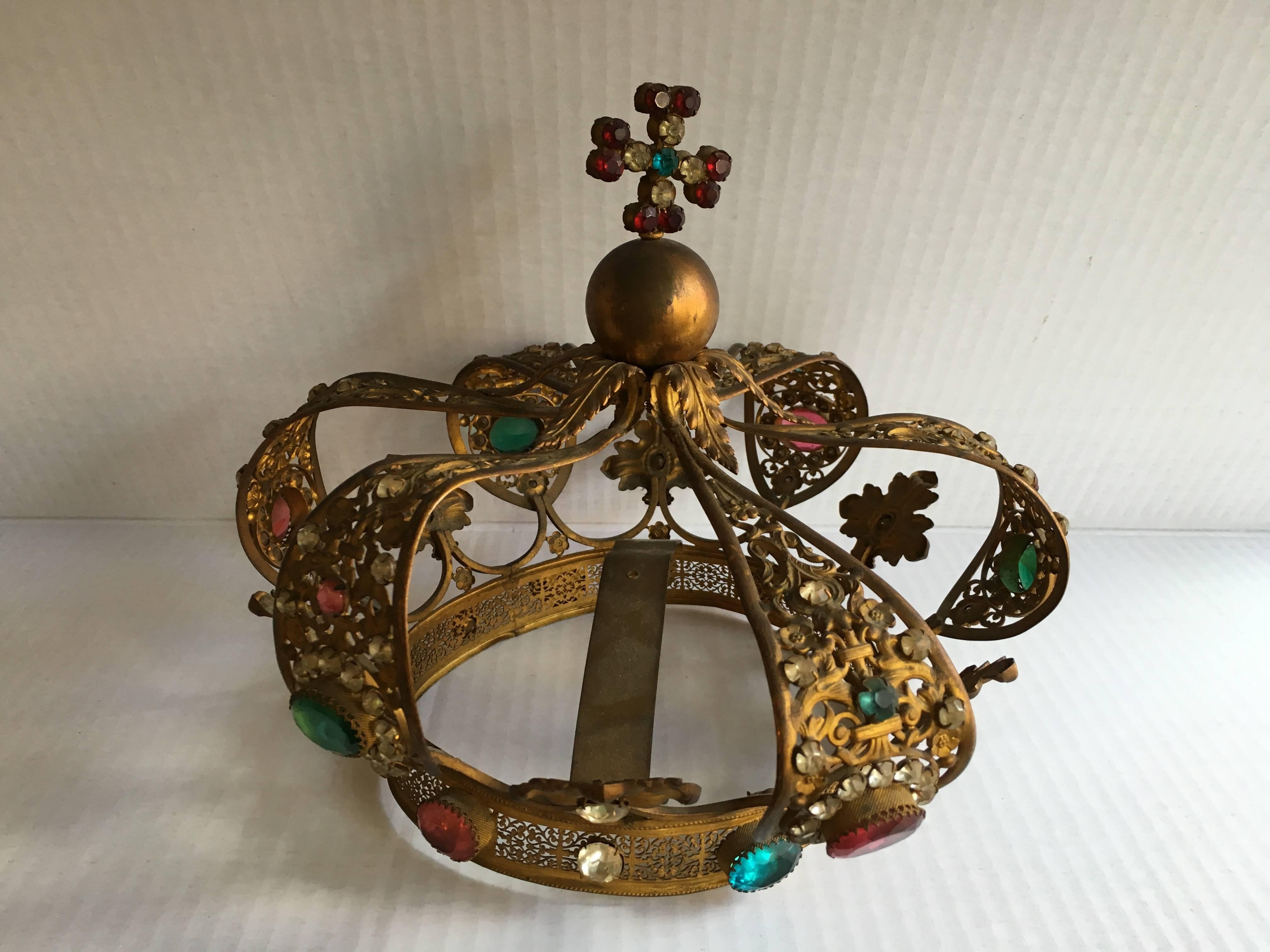 A large religious santos crown with filigree metal and multi colored paste stones.
