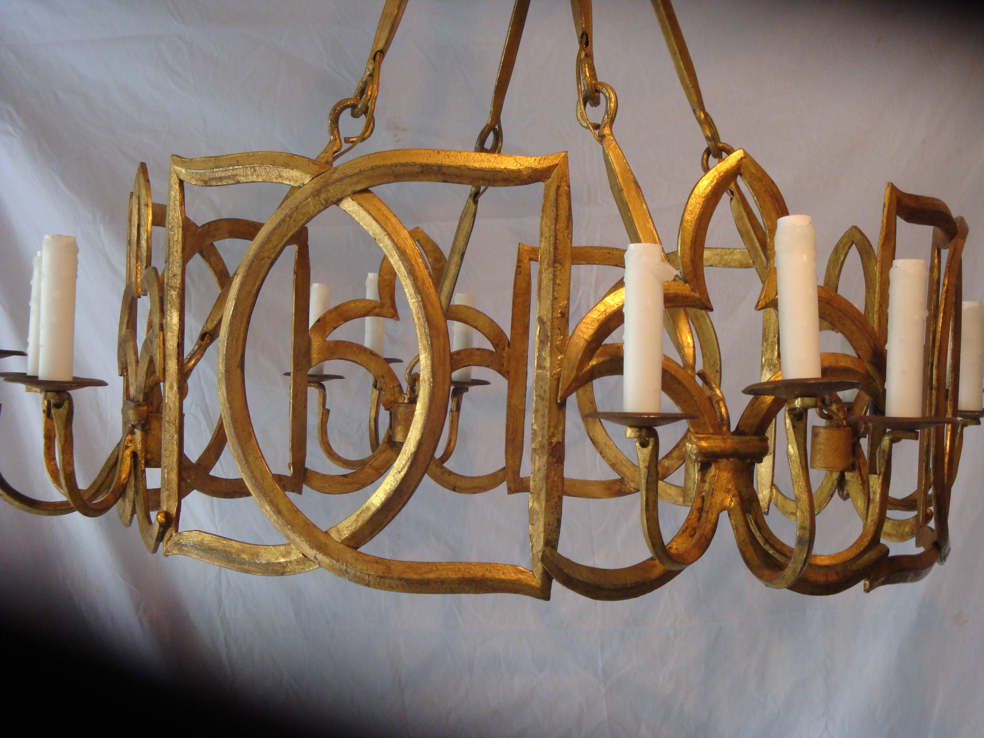 This is a gilt metal twelve-light chandelier with geometric and fleur-de-lis design.