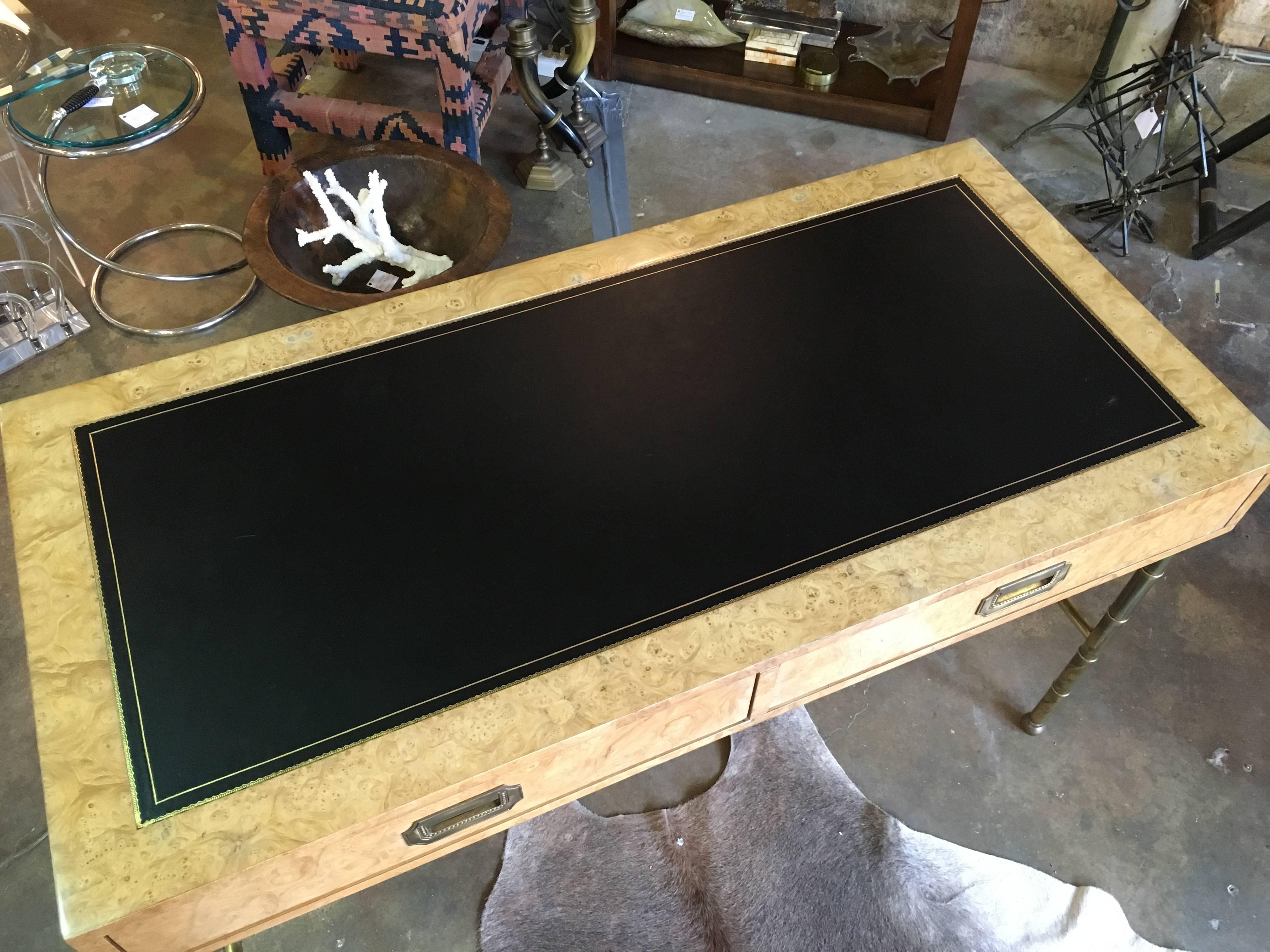 A Mastercraft burled wood and brass desk with a black leather top. Campaign style hardware with two functioning and two faux drawers. Custom glass piece for the top of desk.