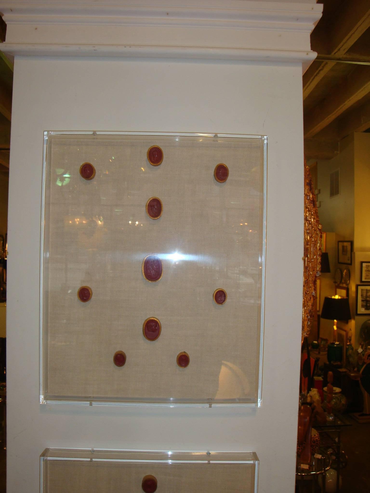 This is a set of three late 1800 red waxed gilt seal intaglios mounted on linen in a Lucite shadow box. They depict different male and female heads or busts.