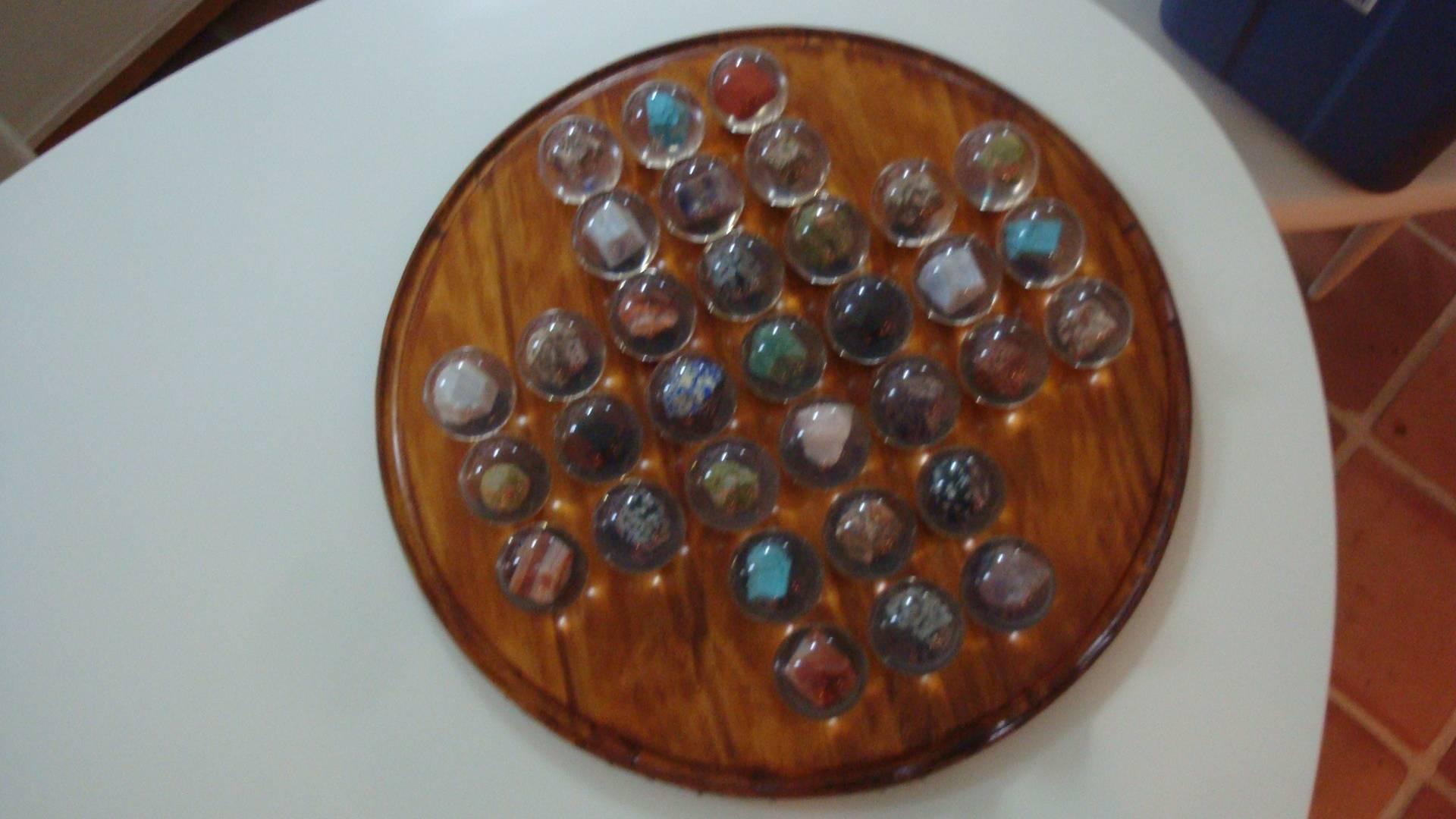 This is a large South African (Lucite marble embedded with different geodes) board game of Solitaire. The wood board has indented areas for each marble
33 balls included.