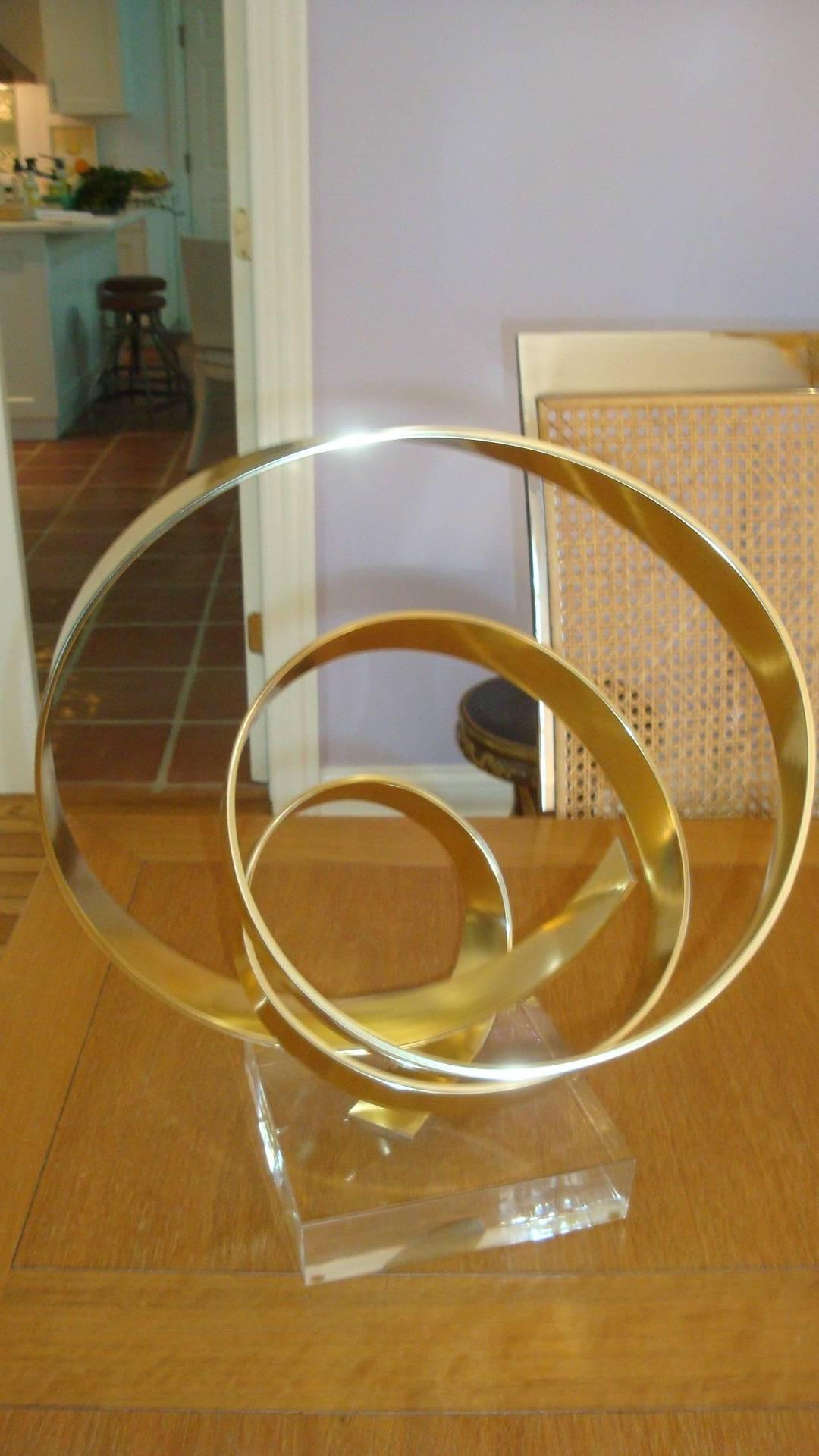 This is a 1979, brass abstract sculpture on Lucite by Dan Murphy.